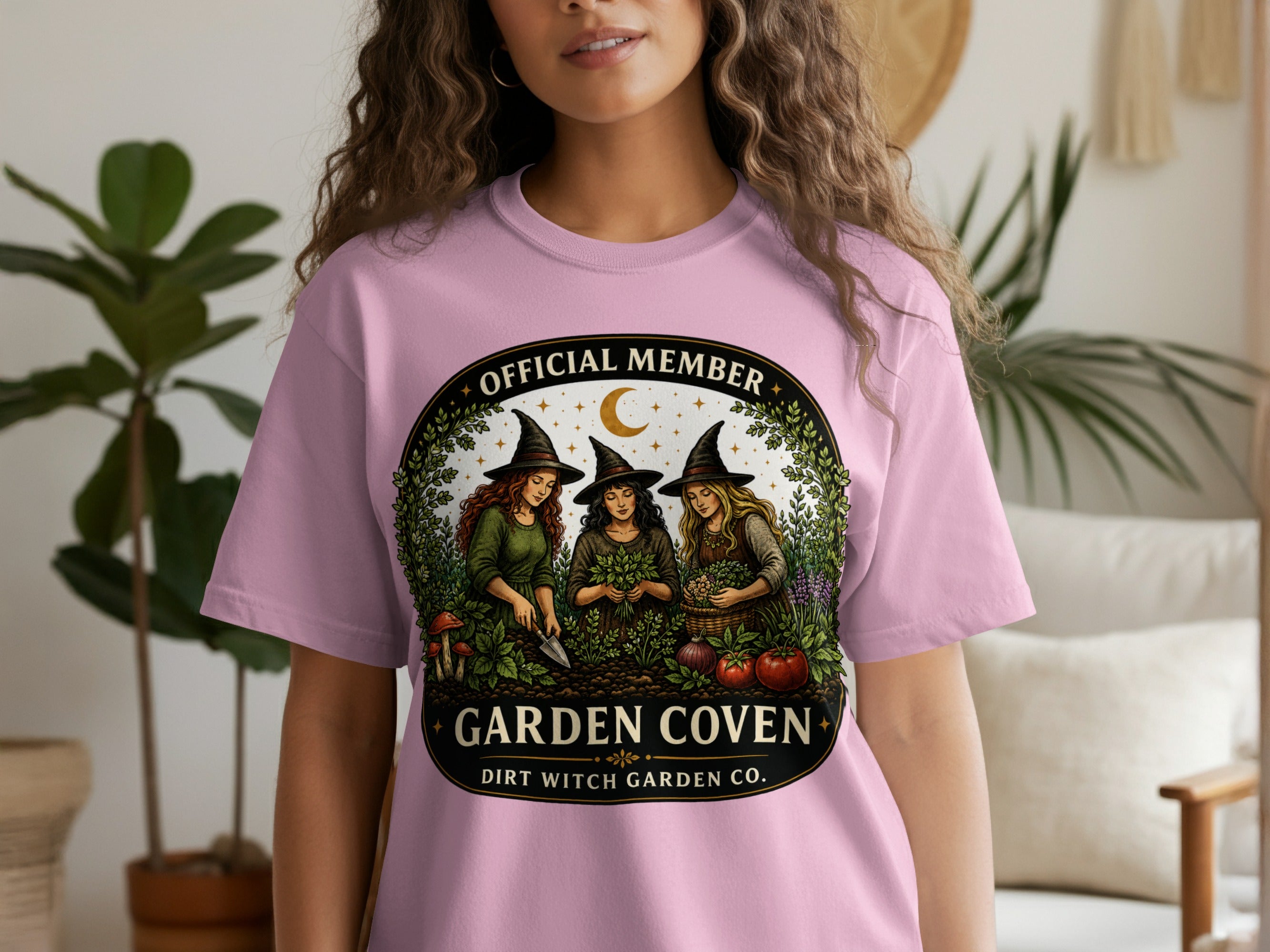 Pink t-shirt with "Garden Coven" and "Dirt Witch Garden Co." text and witch garden graphic.