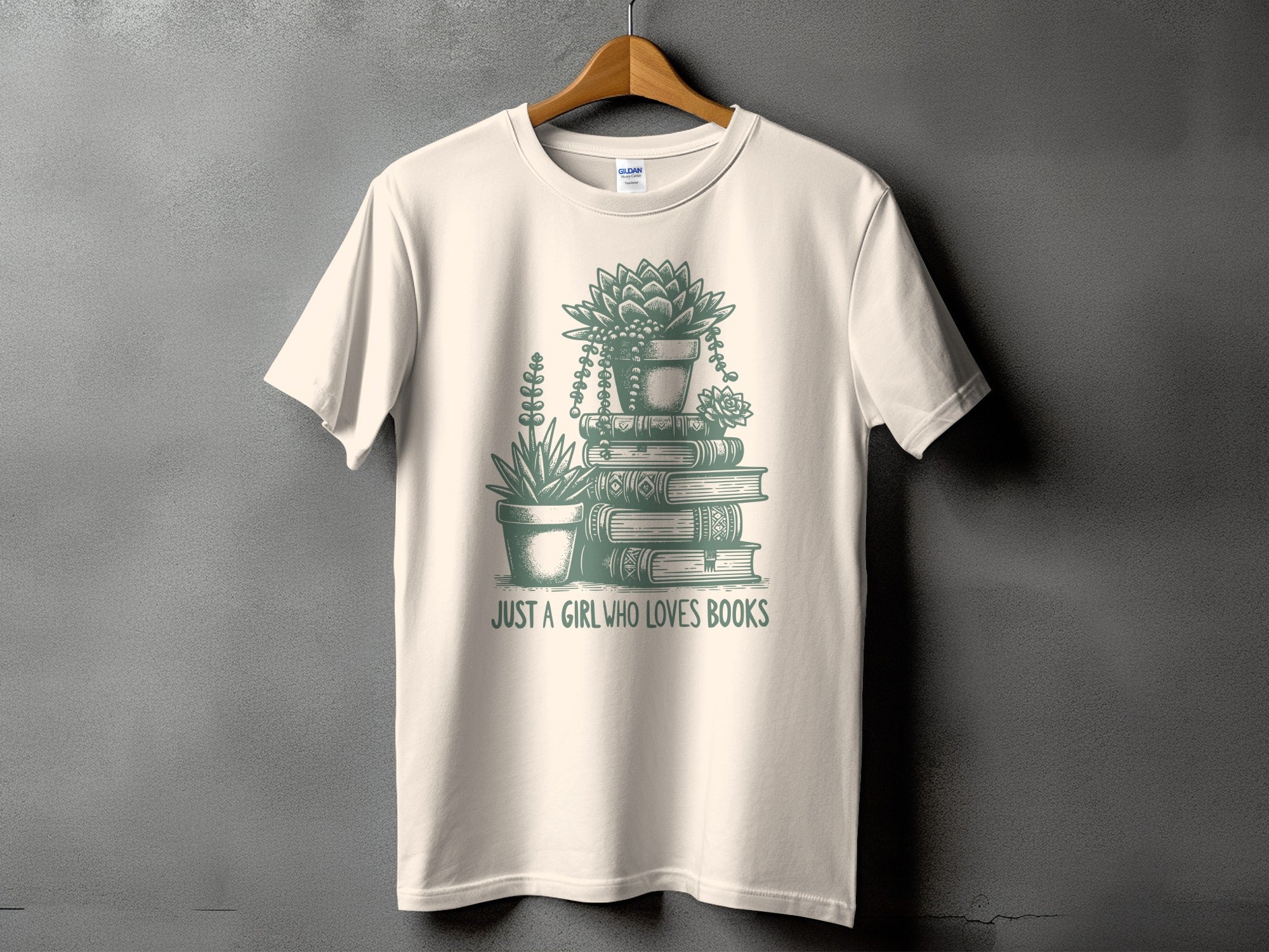 Cream t-shirt with green graphic of potted succulents on stacked books and text "JUST A GIRL WHO LOVES BOOKS".