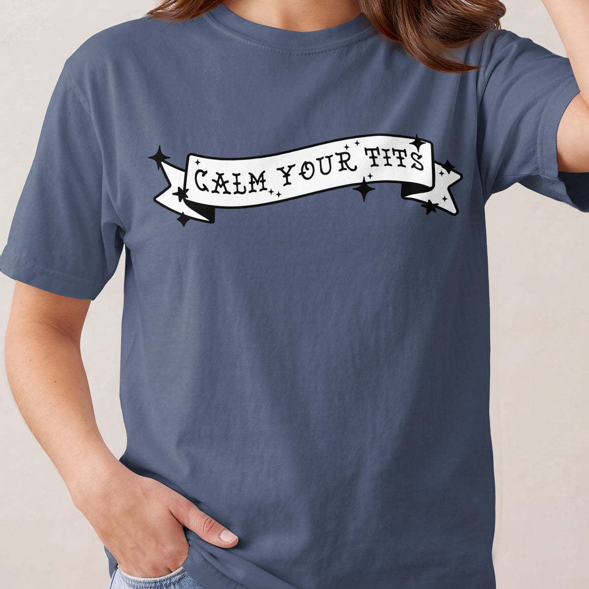 Blue t-shirt with black text banner reading "CALM YOUR TITS".