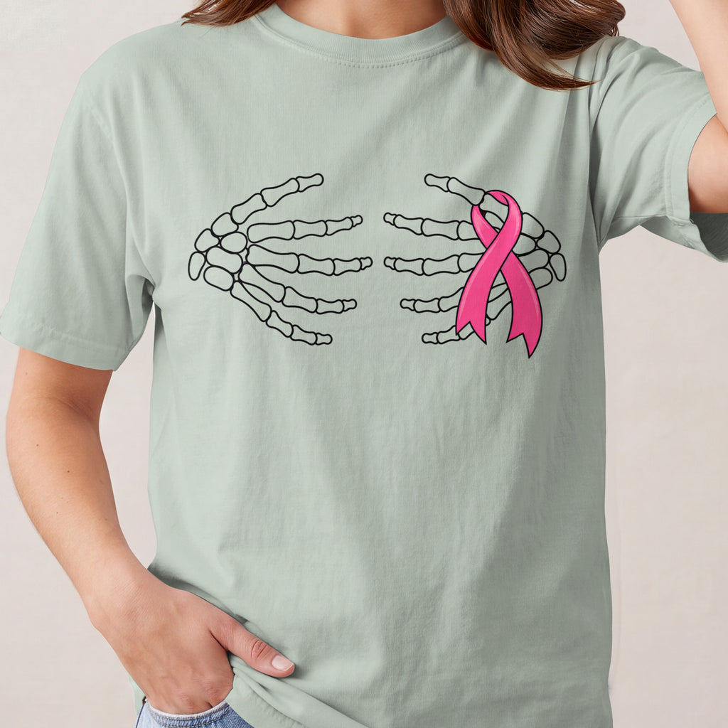 Skeleton hands embrace a pink ribbon on a pale green t-shirt.