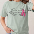 Skeleton hands embrace a pink ribbon on a pale green t-shirt.