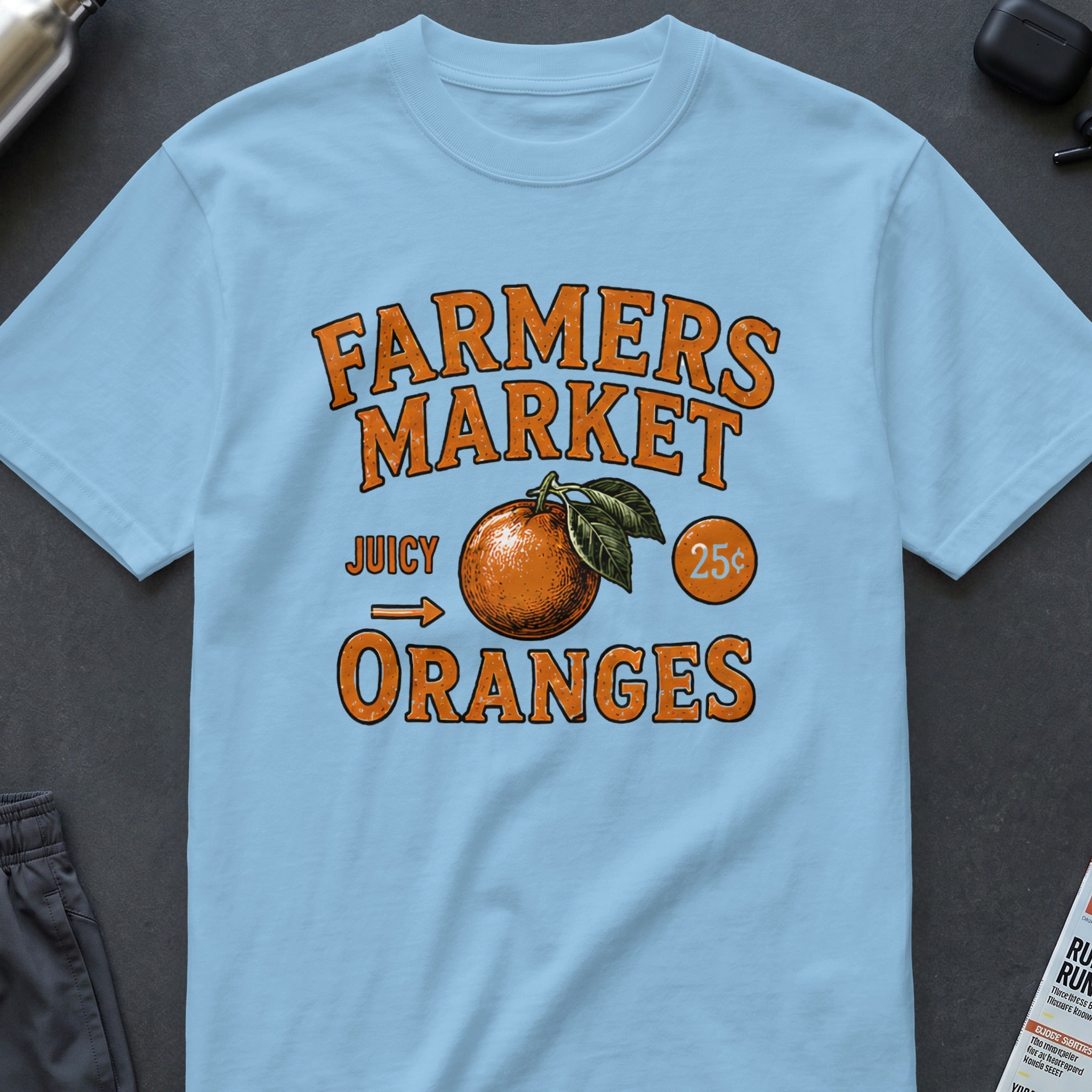 Light blue t-shirt with "FARMERS MARKET JUICY ORANGES 25¢" text and an orange graphic.