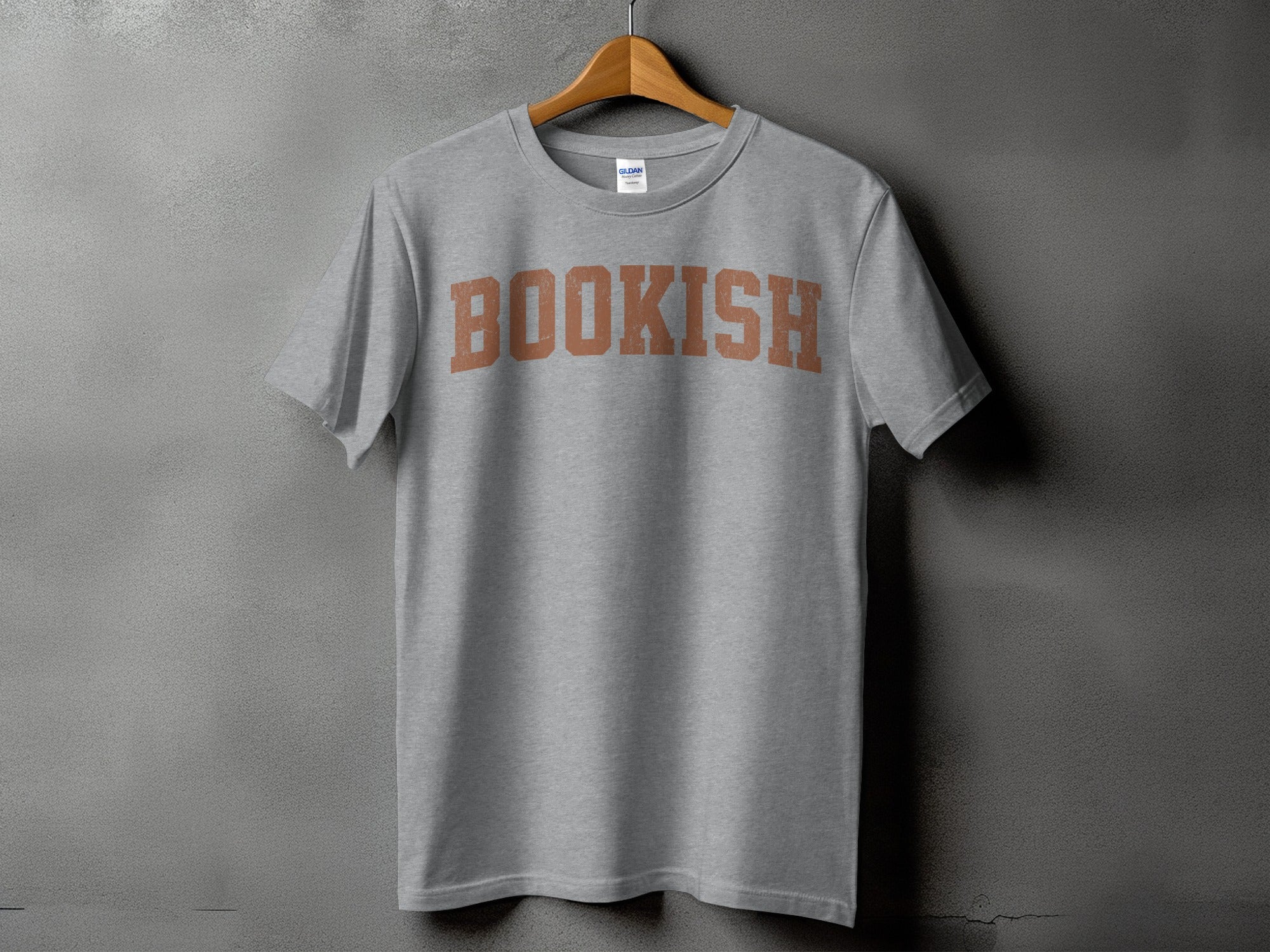 Grey t-shirt with brown "BOOKISH" text, hanging on a wooden hanger.