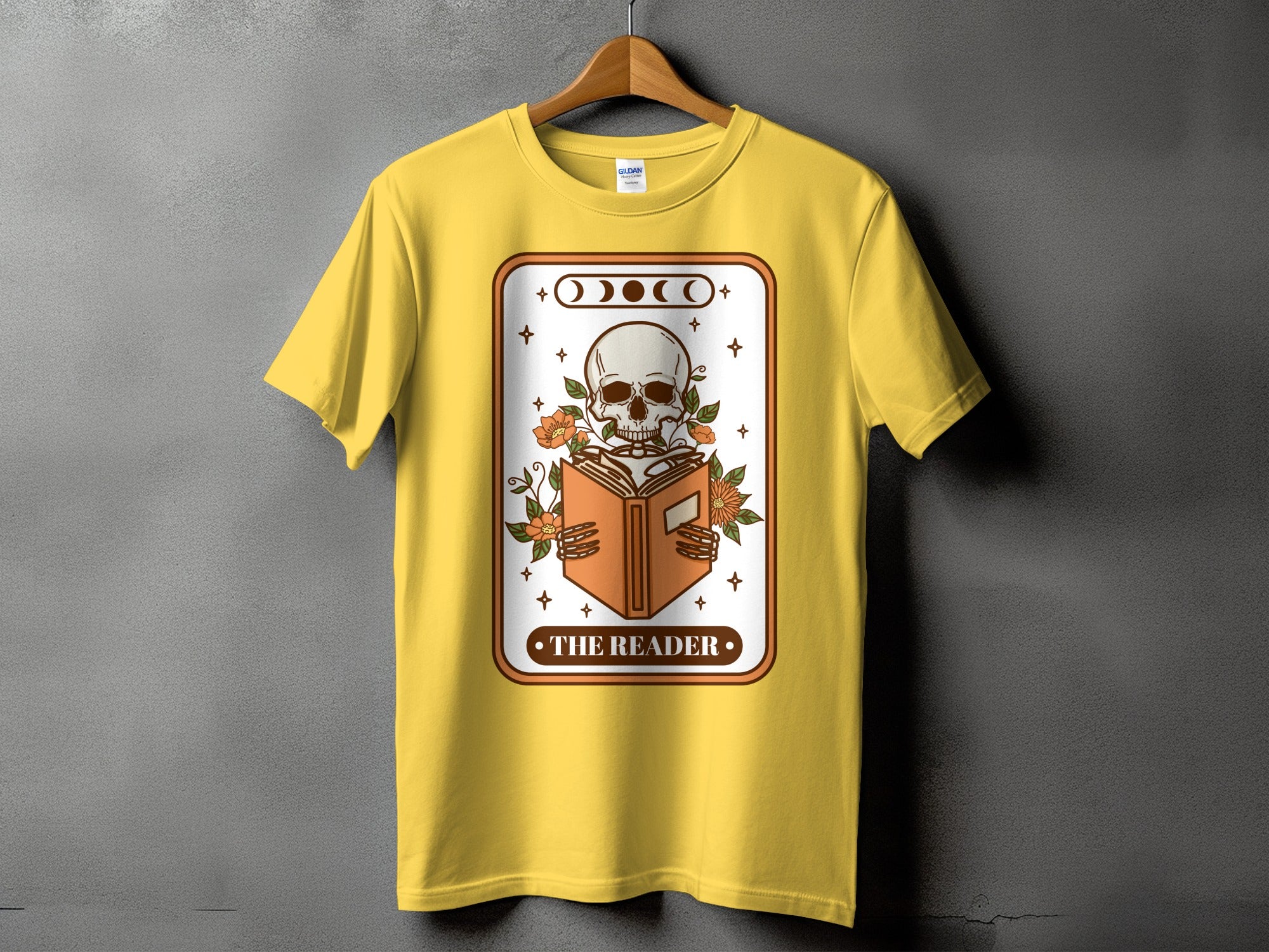 Yellow t-shirt with a skeleton reading a book and moon phases graphic.