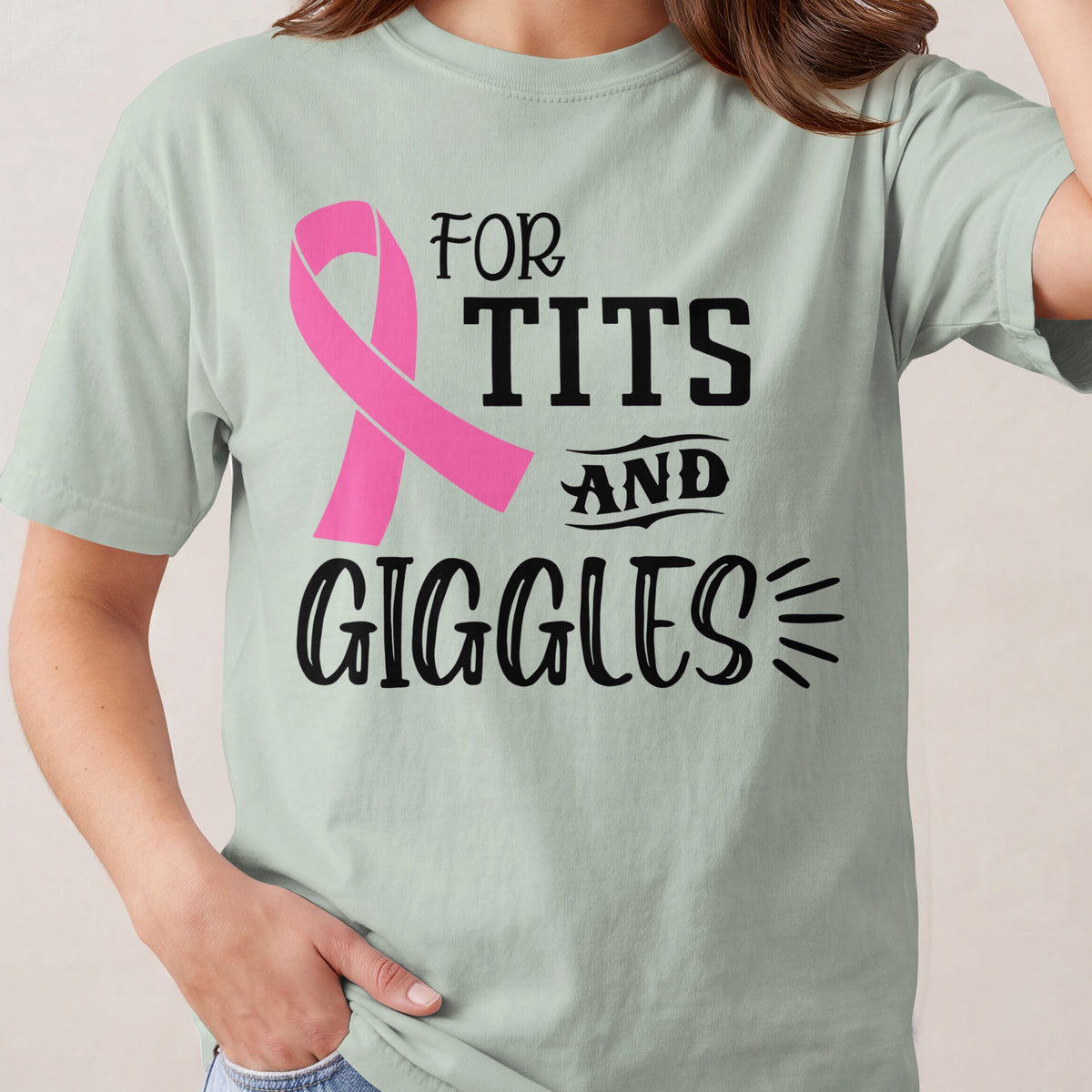 Light green t-shirt with a pink ribbon and text reading "FOR TITS AND GIGGLES".