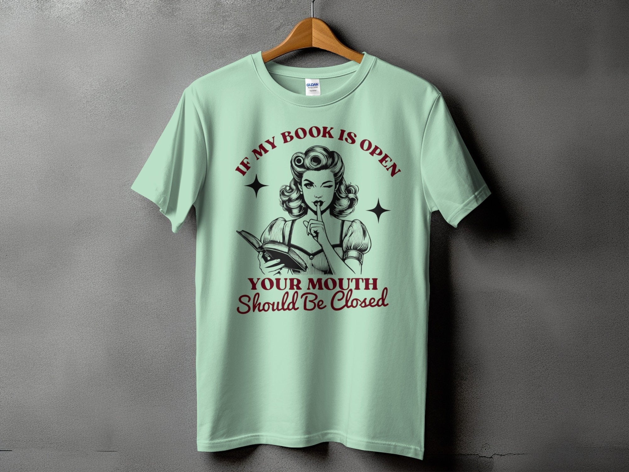 T-shirt graphic with vintage woman reading, text "If my book is open, your mouth should be closed."
