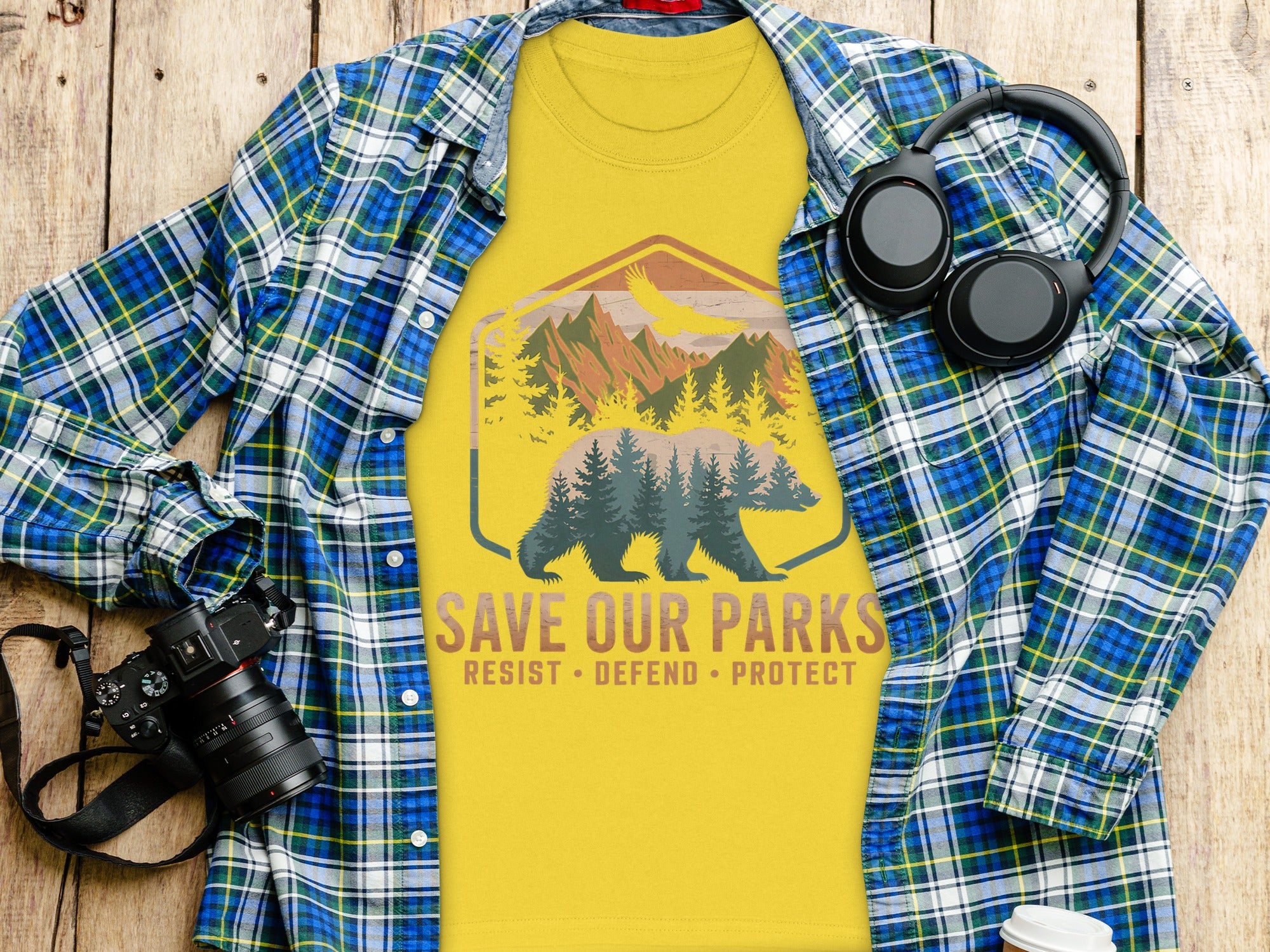 Yellow t-shirt with bear, eagle, and mountains graphic and text "SAVE OUR PARKS RESIST DEFEND PROTECT".