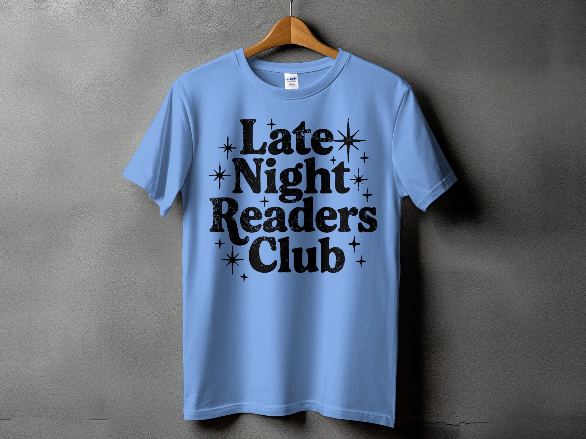 Light blue t-shirt with black text "Late Night Readers Club" and star graphics.