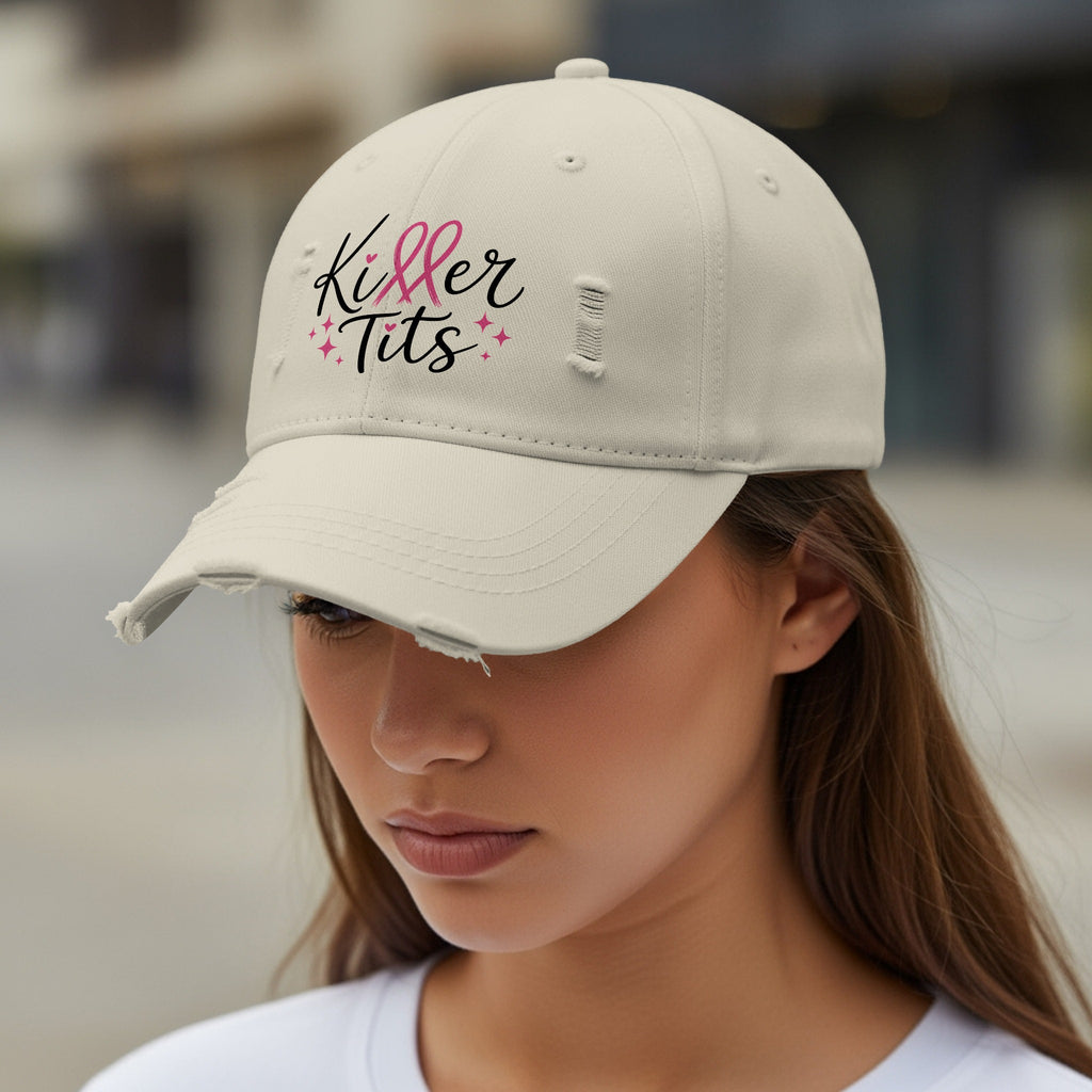 Light beige distressed baseball cap with black text "Killer Tits" and pink stars.