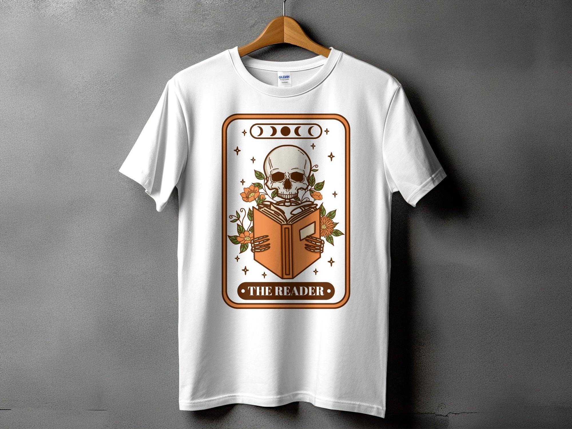 White t-shirt with graphic of a skeleton reading a book, text "THE READER."