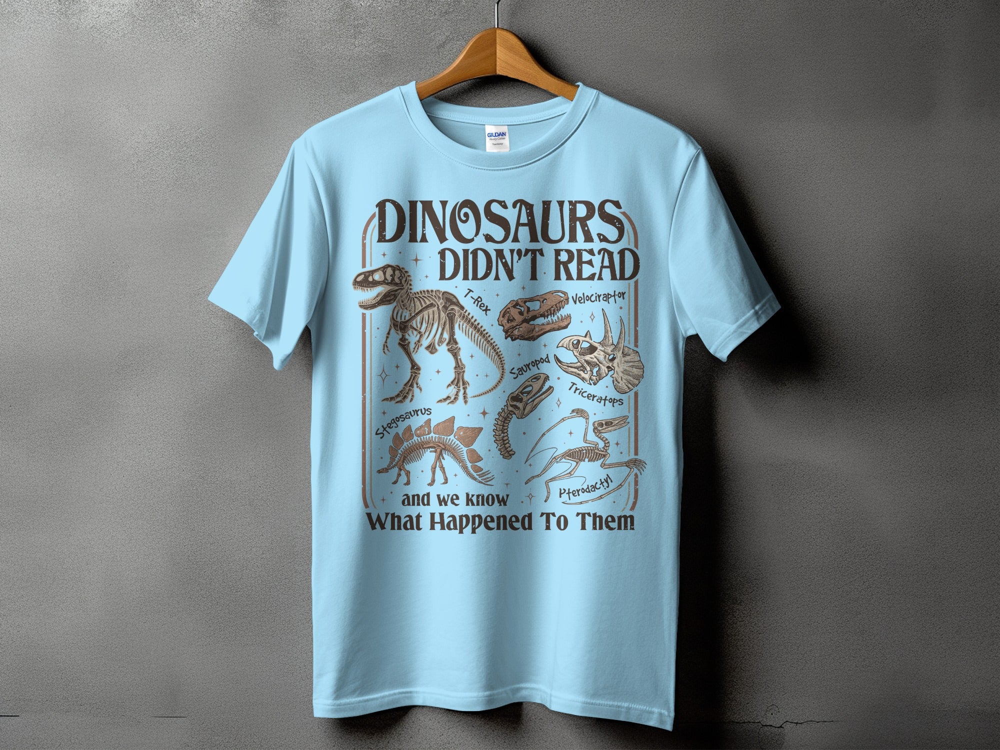 Light blue t-shirt with "Dinosaurs Didn't Read" and dinosaur skeletons.