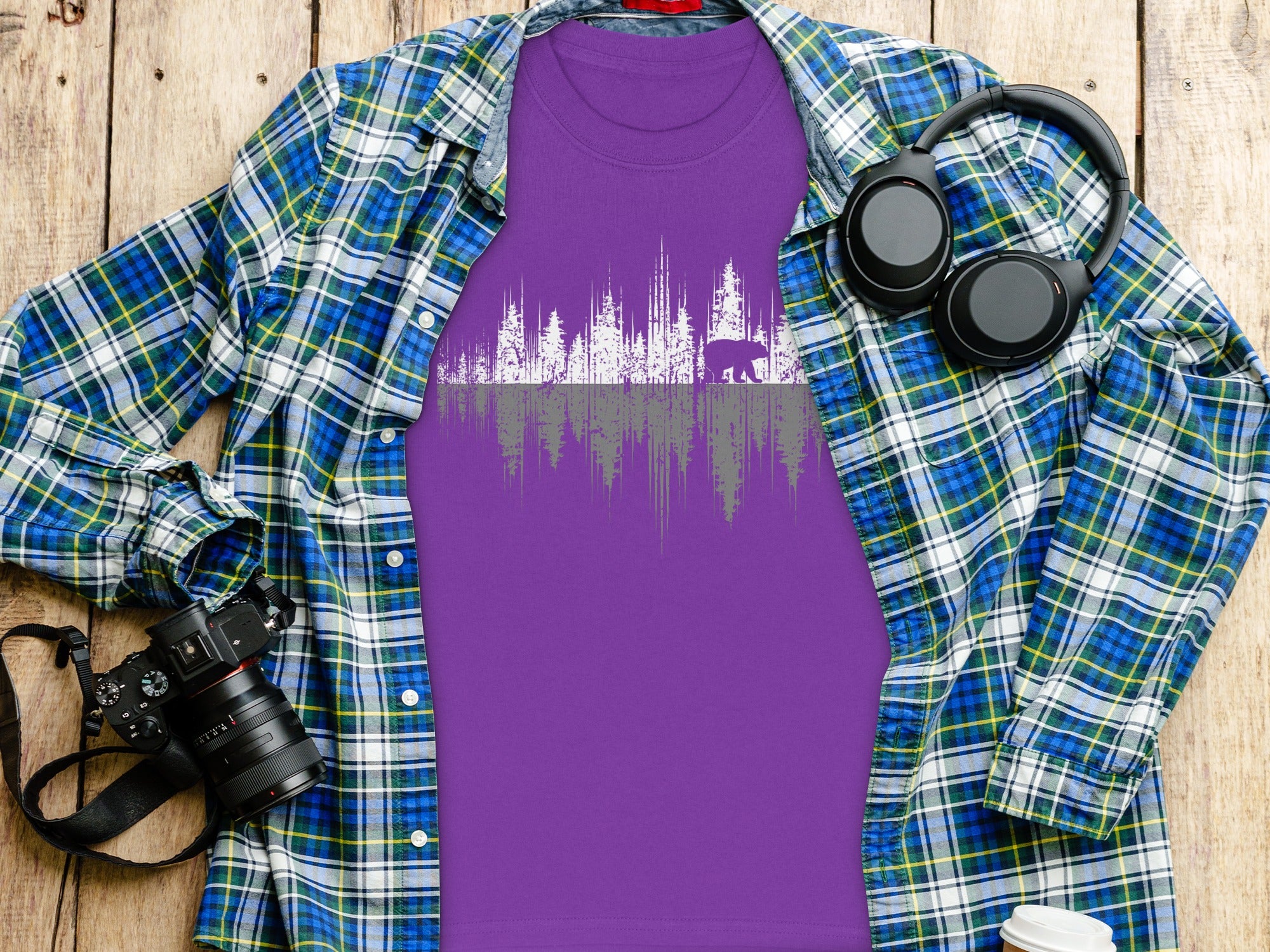 Purple t-shirt with bear and trees graphic, layered under a plaid shirt.