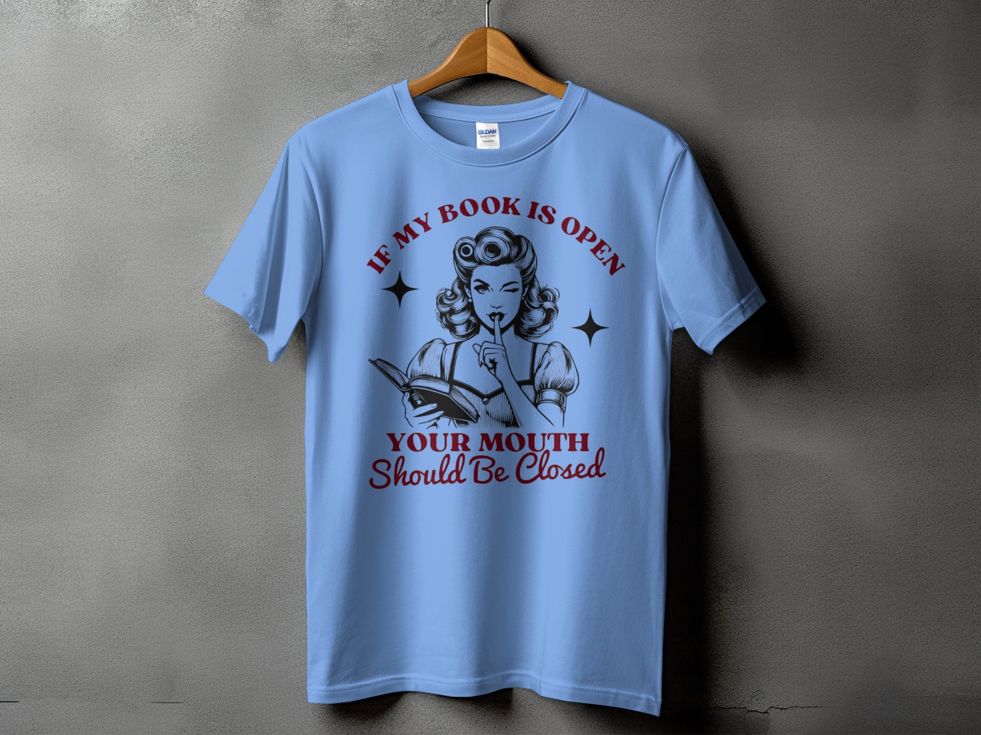 Blue t-shirt with graphic of woman reading and text "If my book is open your mouth should be closed".