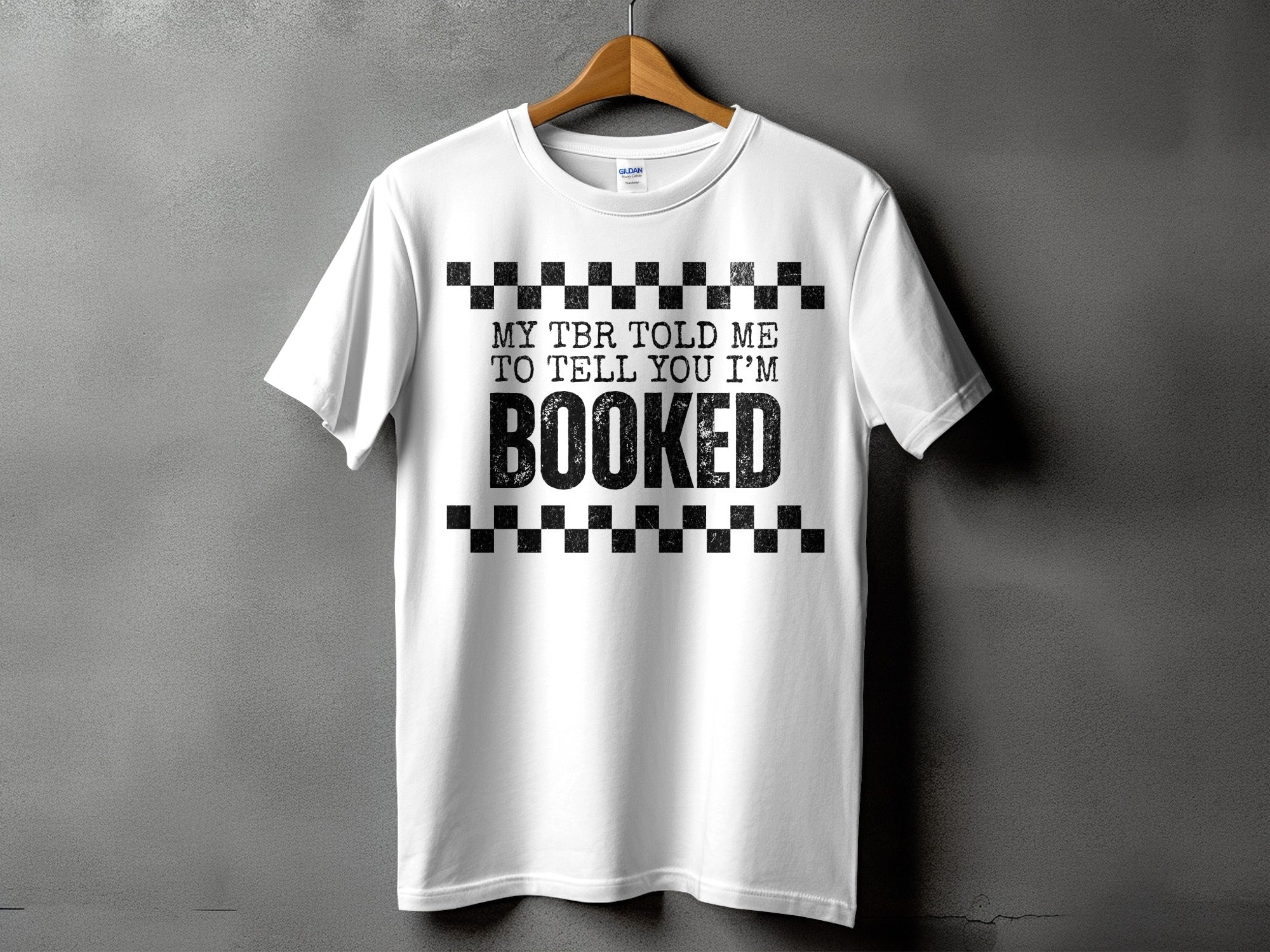 White t-shirt with black text reading "MY TBR TOLD ME TO TELL YOU I'M BOOKED".