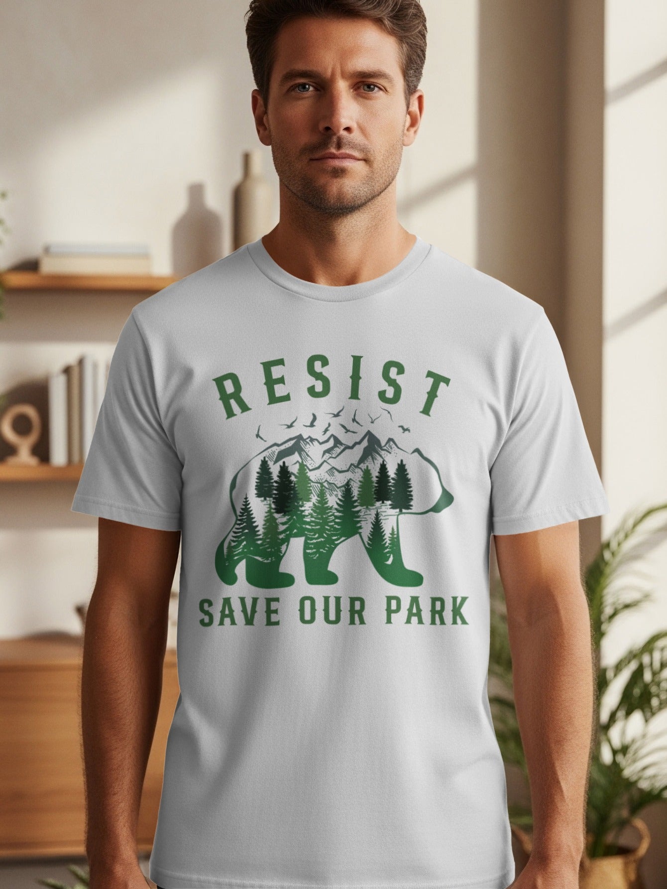 White t-shirt with green text "RESIST SAVE OUR PARK" and a bear silhouette filled with trees and mountains.