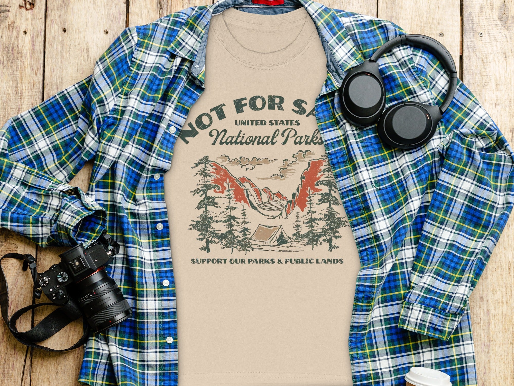 T-shirt with "United States National Parks" graphic, plaid shirt, camera, and headphones.