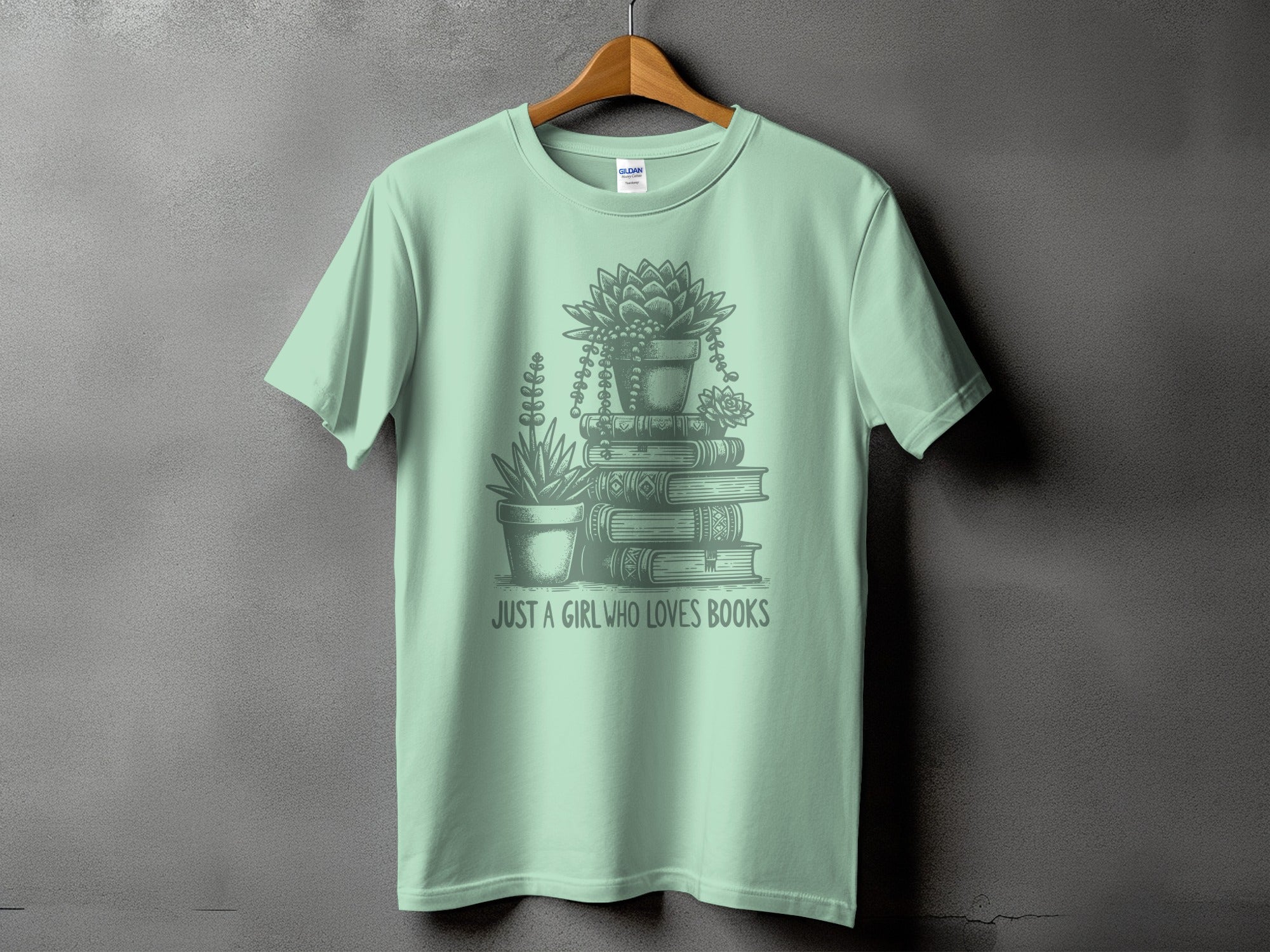 Light green t-shirt with a drawing of books and plants, text "JUST A GIRL WHO LOVES BOOKS".