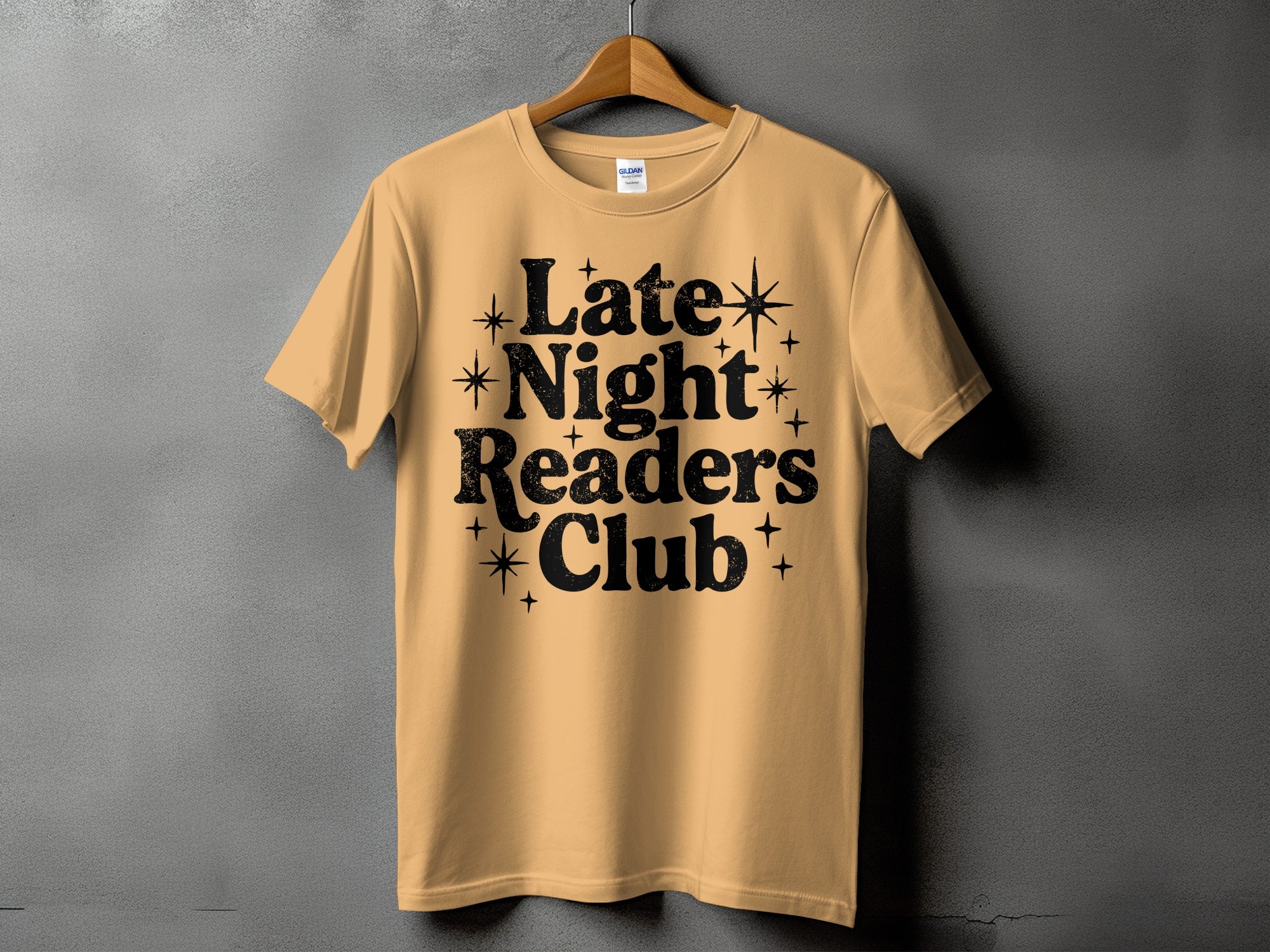 Peach t-shirt with black text "Late Night Readers Club" and decorative stars.