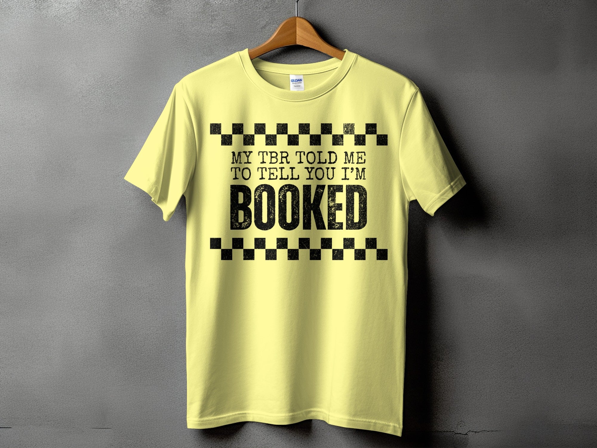 Yellow t-shirt with black text "MY TBR TOLD ME TO TELL YOU I'M BOOKED".