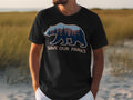 Black t-shirt featuring a bear silhouette filled with a forest and mountain landscape and text "SAVE OUR PARKS".