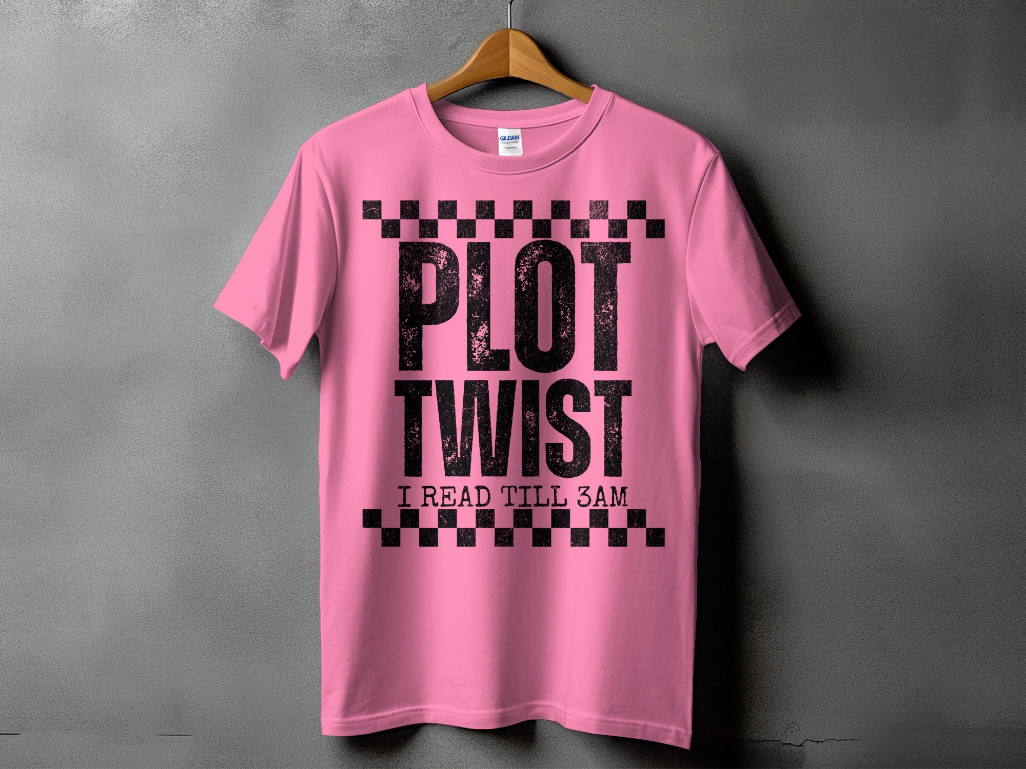 Pink t-shirt with black text "PLOT TWIST I READ TILL 3AM" and checkered accents.