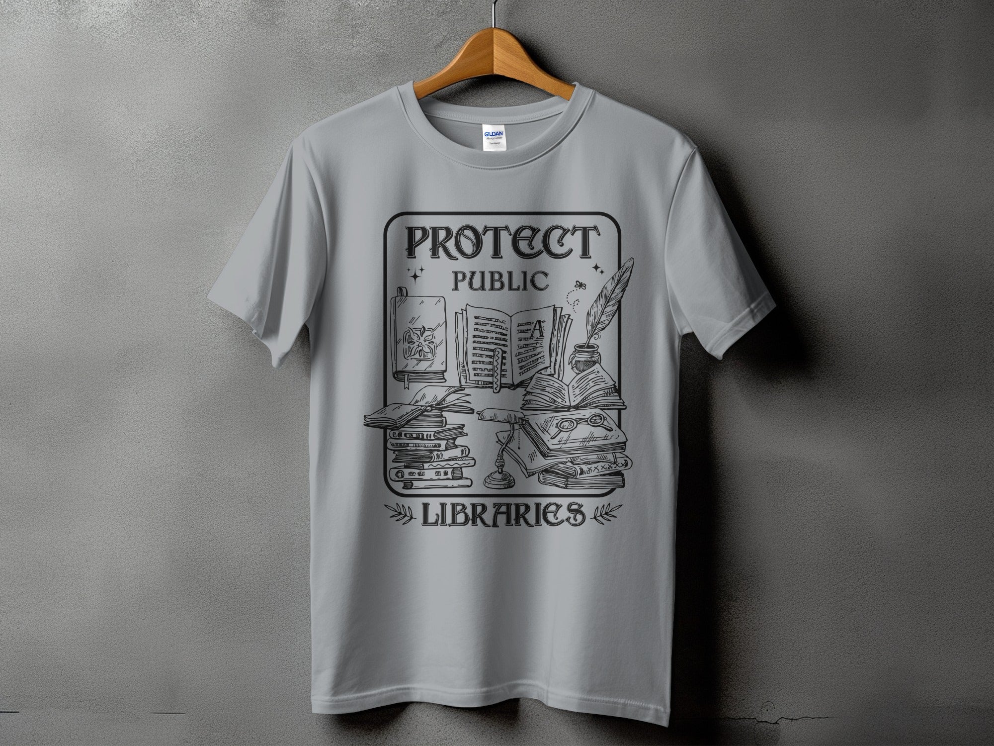 Grey t-shirt with "Protect Public Libraries" graphic featuring stacked books and writing tools.