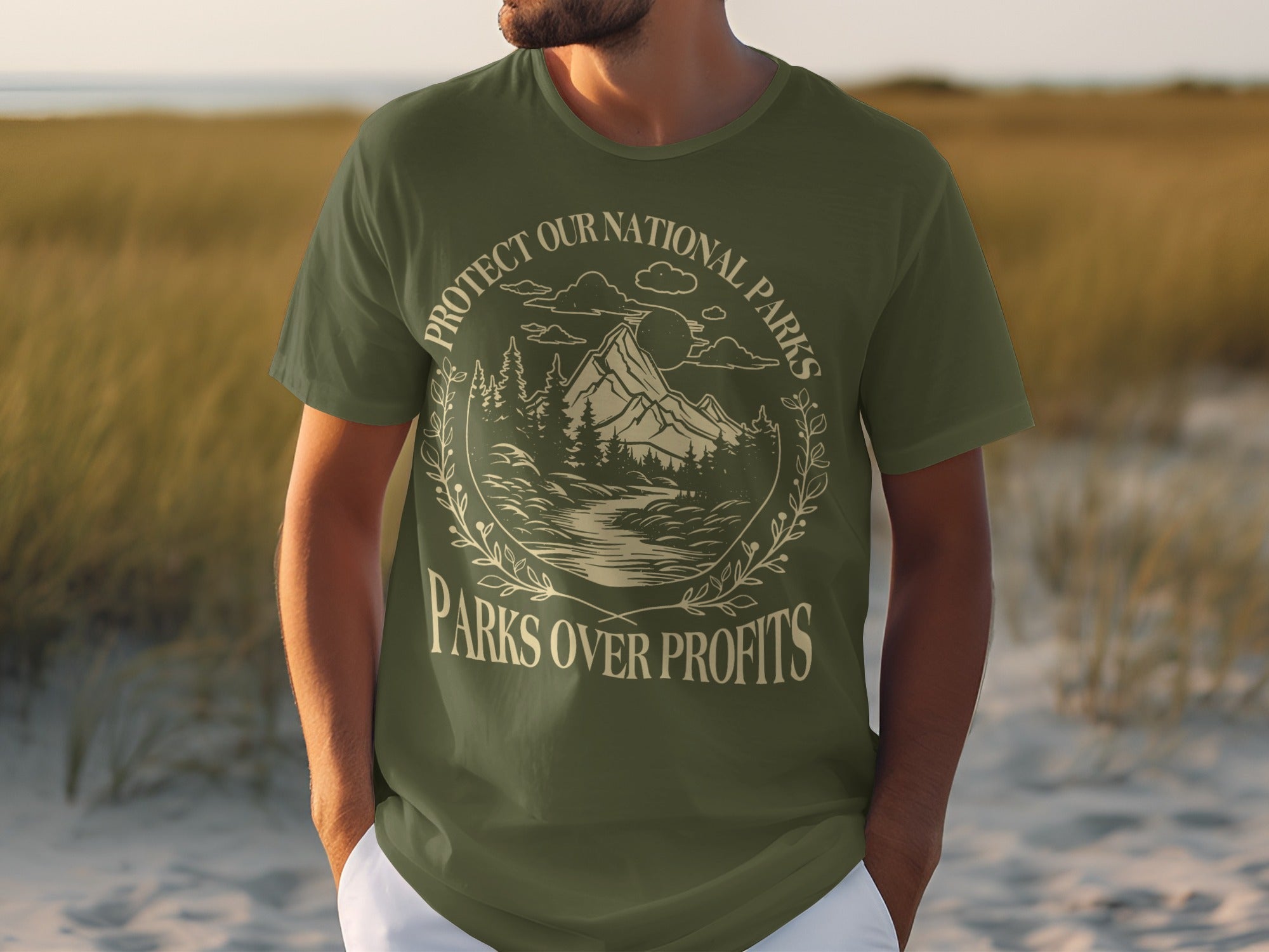 Olive green t-shirt with circular graphic of mountains, trees, water, and text "Protect Our National Parks Parks Over Profits."