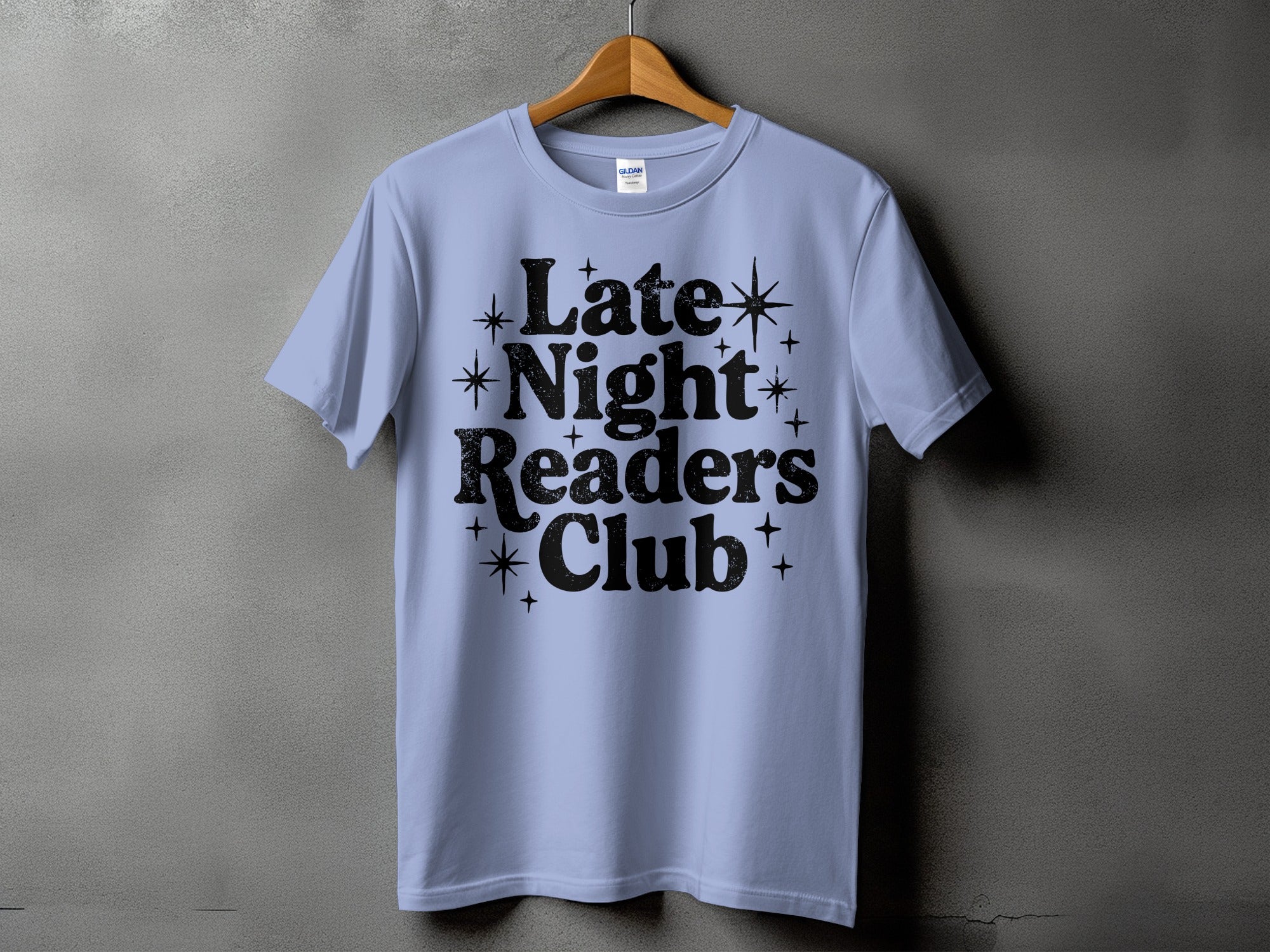 Light blue t-shirt with black text "Late Night Readers Club" and decorative stars.