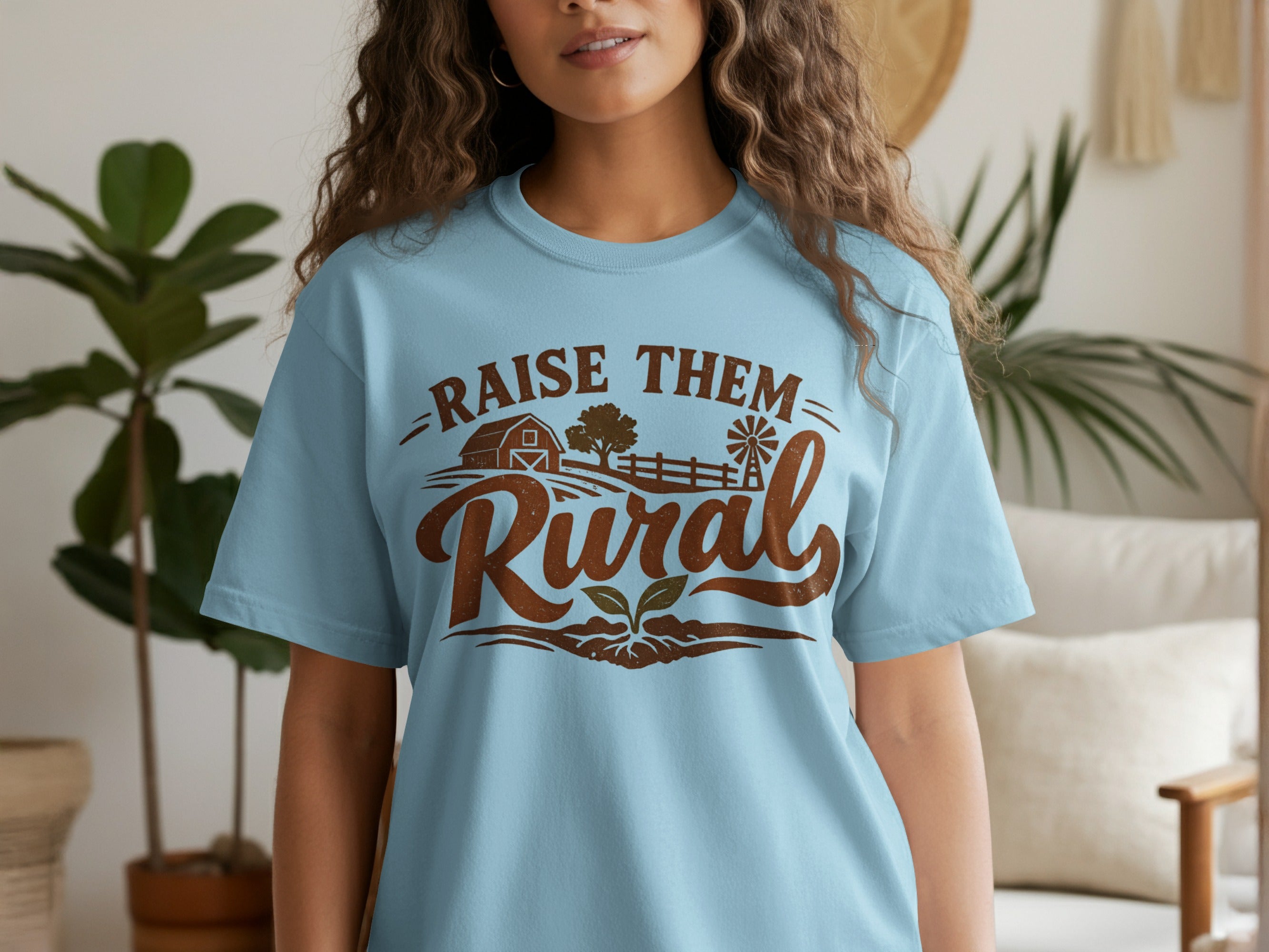 Light blue t-shirt with "RAISE THEM Rural" text and farm-themed graphic.