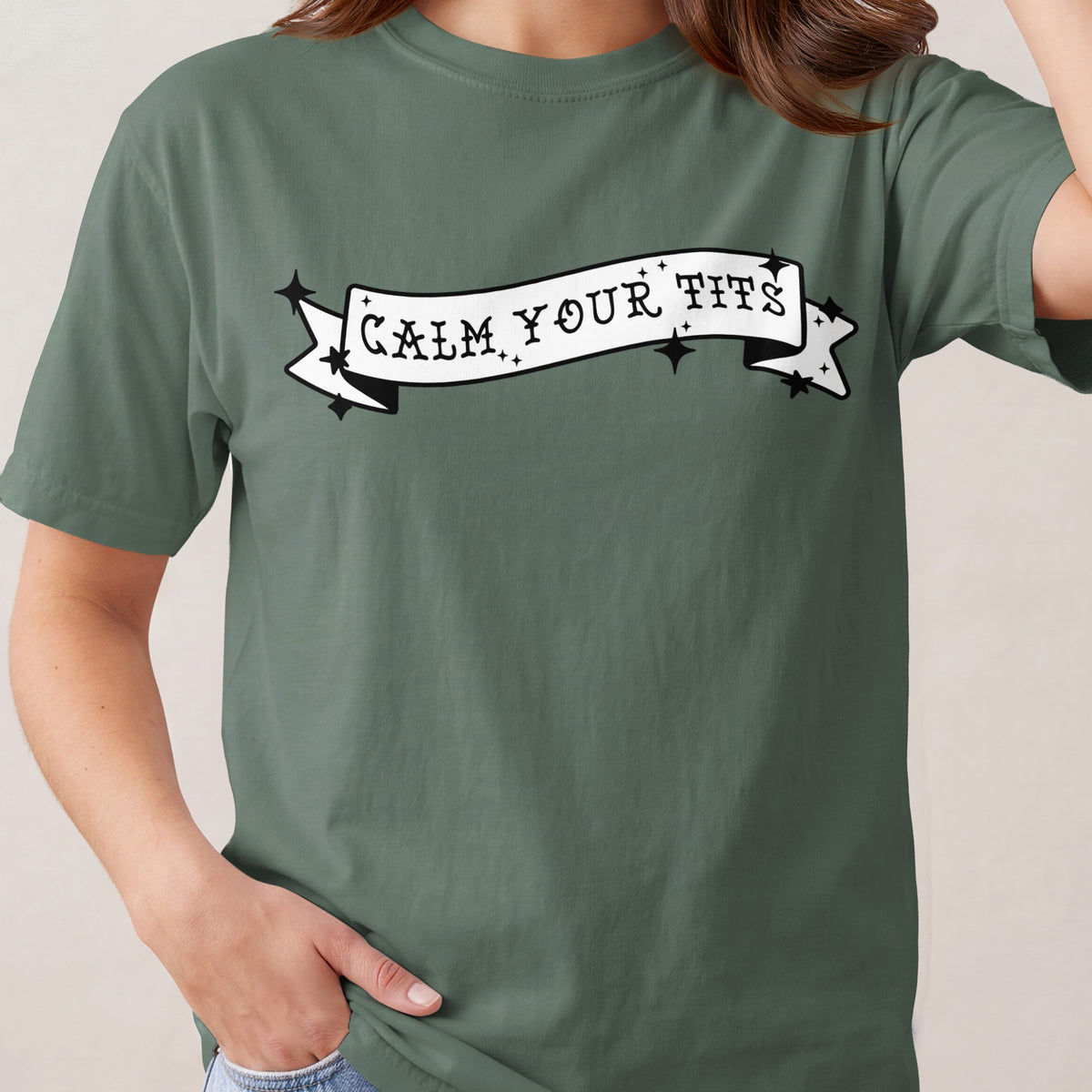 Green t-shirt with "Calm Your Tits" text on a banner graphic.