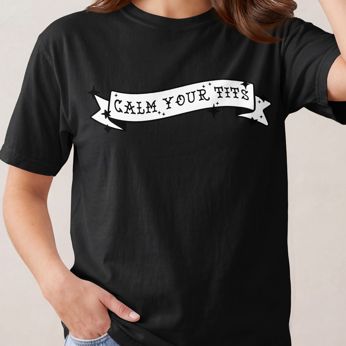 Black t-shirt with white banner graphic reading "CALM YOUR TITS".