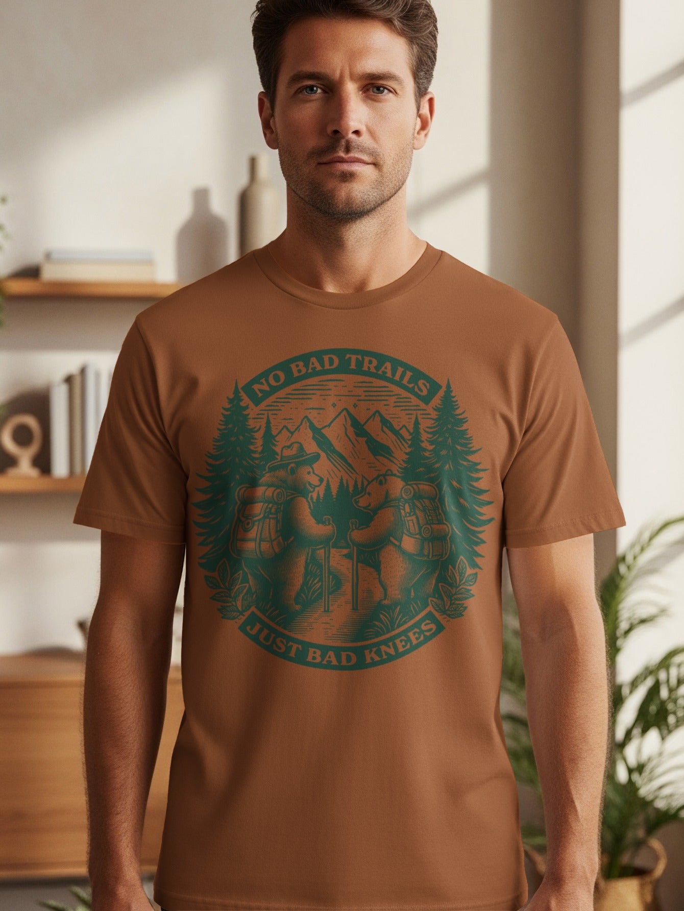 Brown t-shirt with graphic of two bears hiking with text "NO BAD TRAILS JUST BAD KNEES".