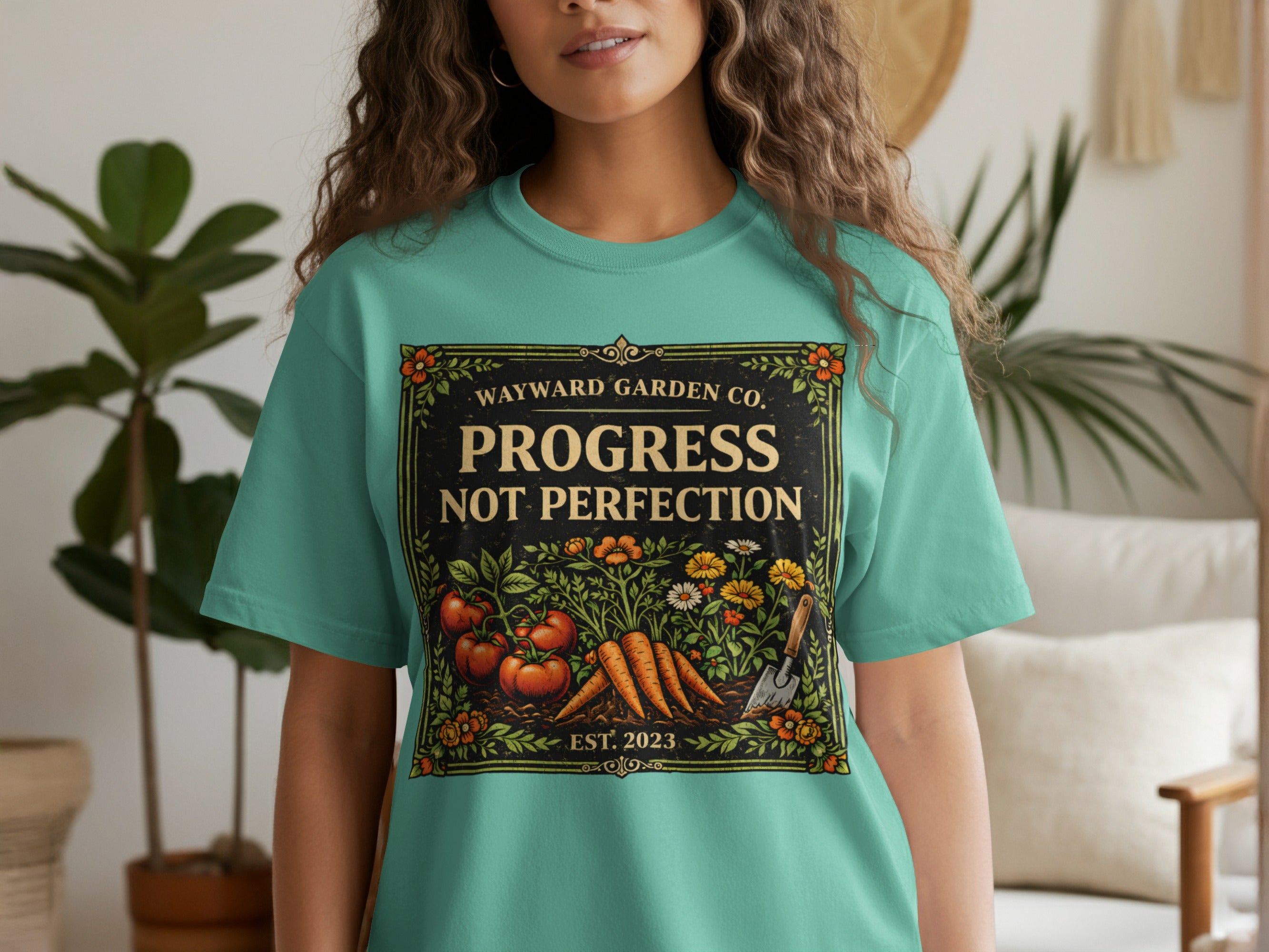 Teal t-shirt with "Wayward Garden Co. PROGRESS NOT PERFECTION" and garden illustration.