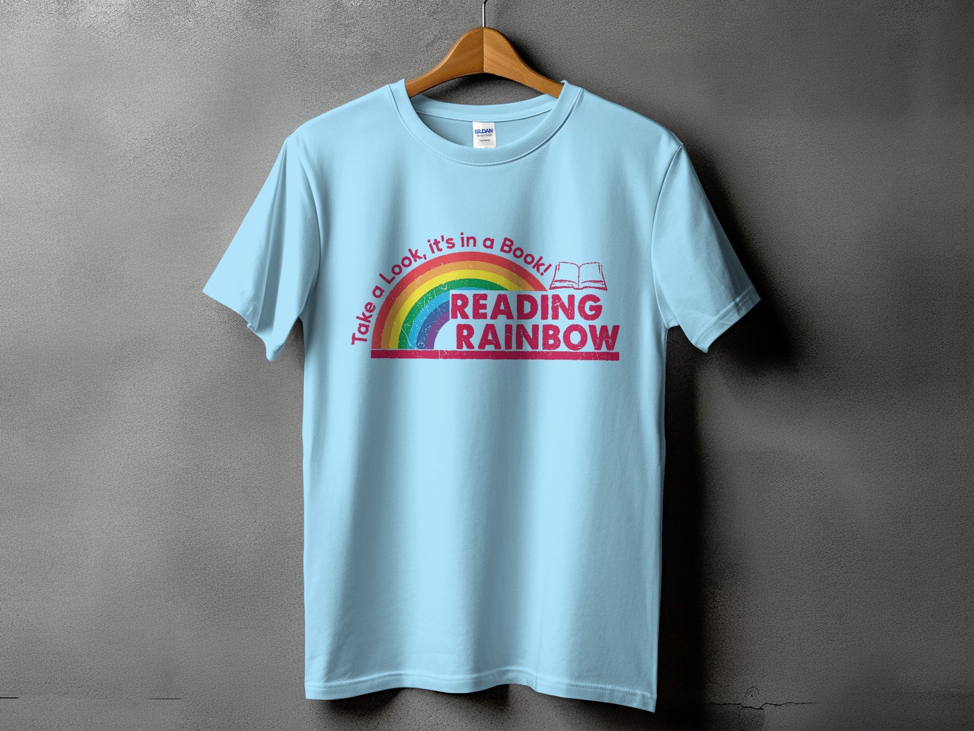 Light blue t-shirt with rainbow and text "Take a Look, it's in a Book! READING RAINBOW"