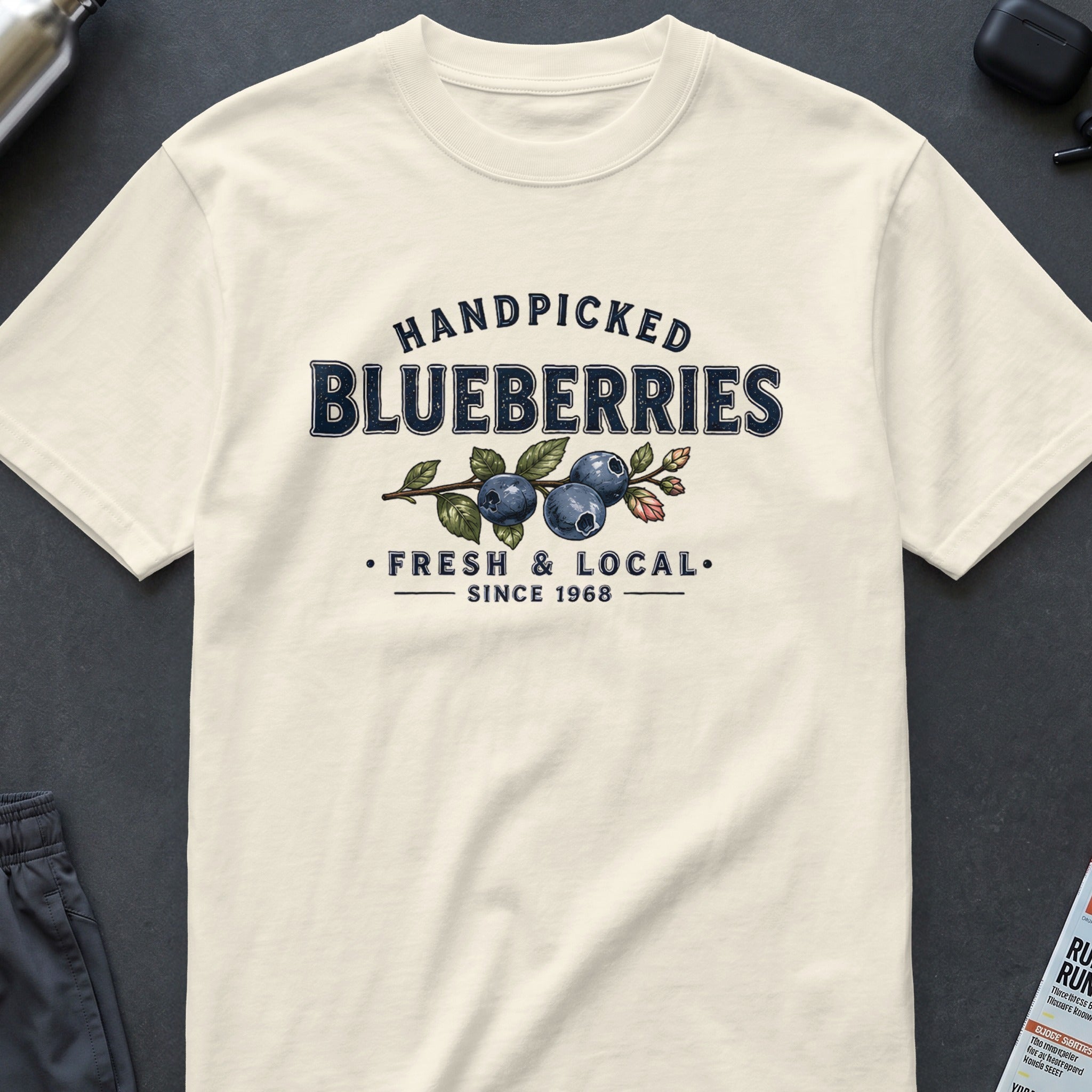Cream t-shirt with "Handpicked Blueberries, Fresh & Local, Since 1968" graphic.
