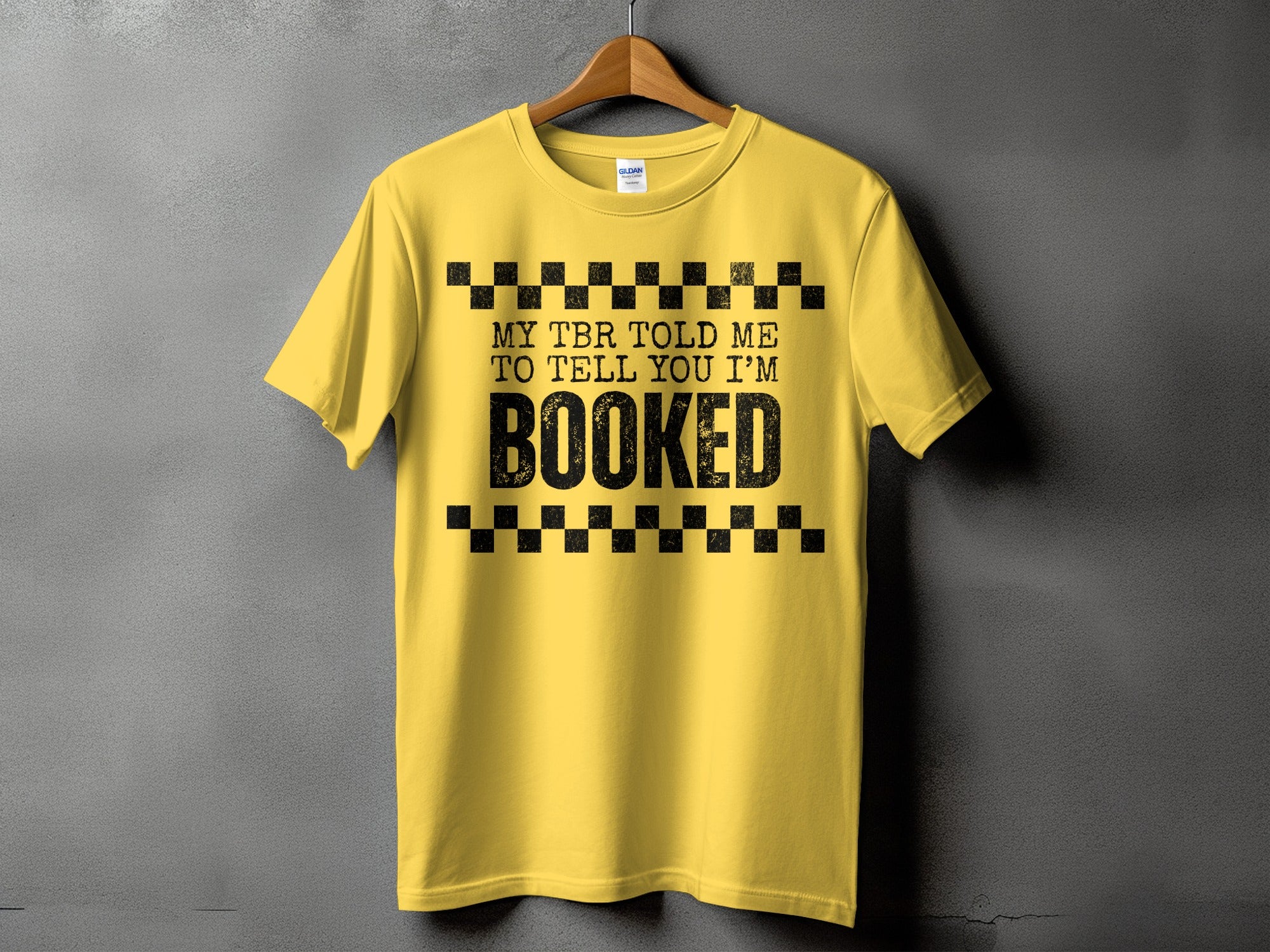 Yellow t-shirt with black text: "MY TBR TOLD ME TO TELL YOU I'M BOOKED".