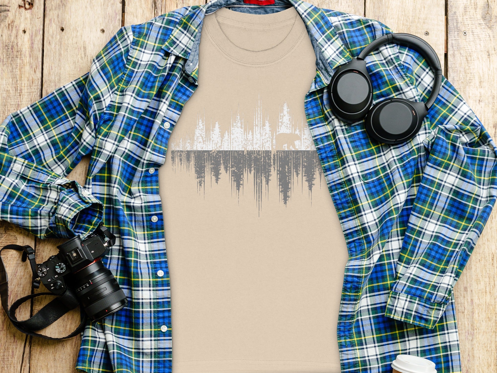 T-shirt with distressed forest graphic and a solitary bear, with open plaid shirt and accessories.