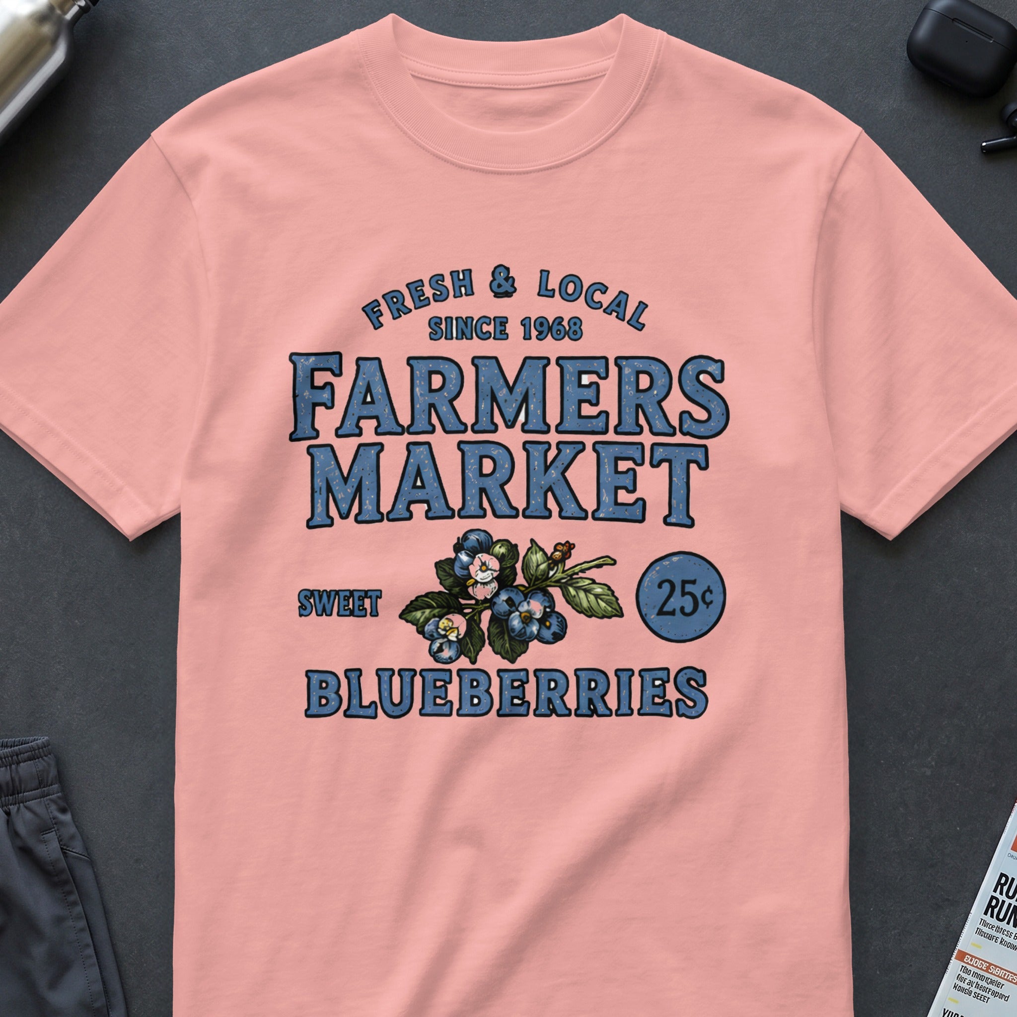 Peach t-shirt with "Fresh & Local Since 1968 Farmers Market Sweet Blueberries 25¢" graphic.