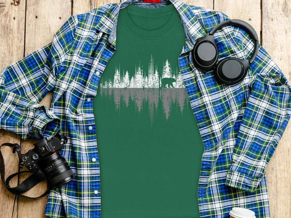 Green t-shirt with white and grey forest silhouette and bear graphic.