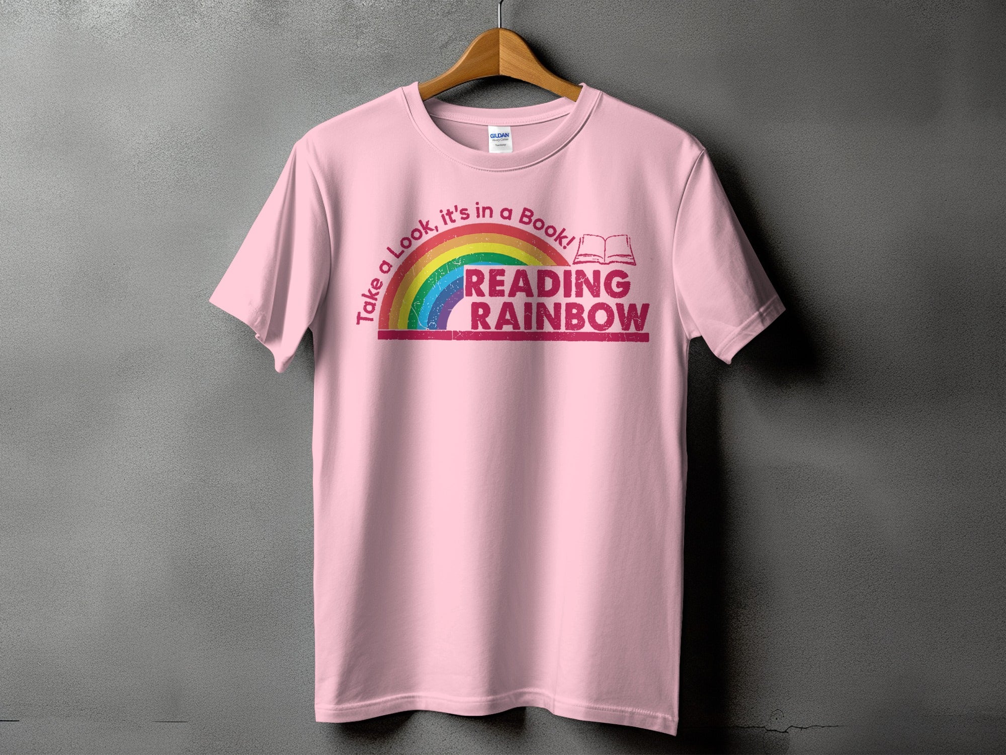 Pink t-shirt with "Take a Look, it's in a Book! READING RAINBOW" text and rainbow graphic.