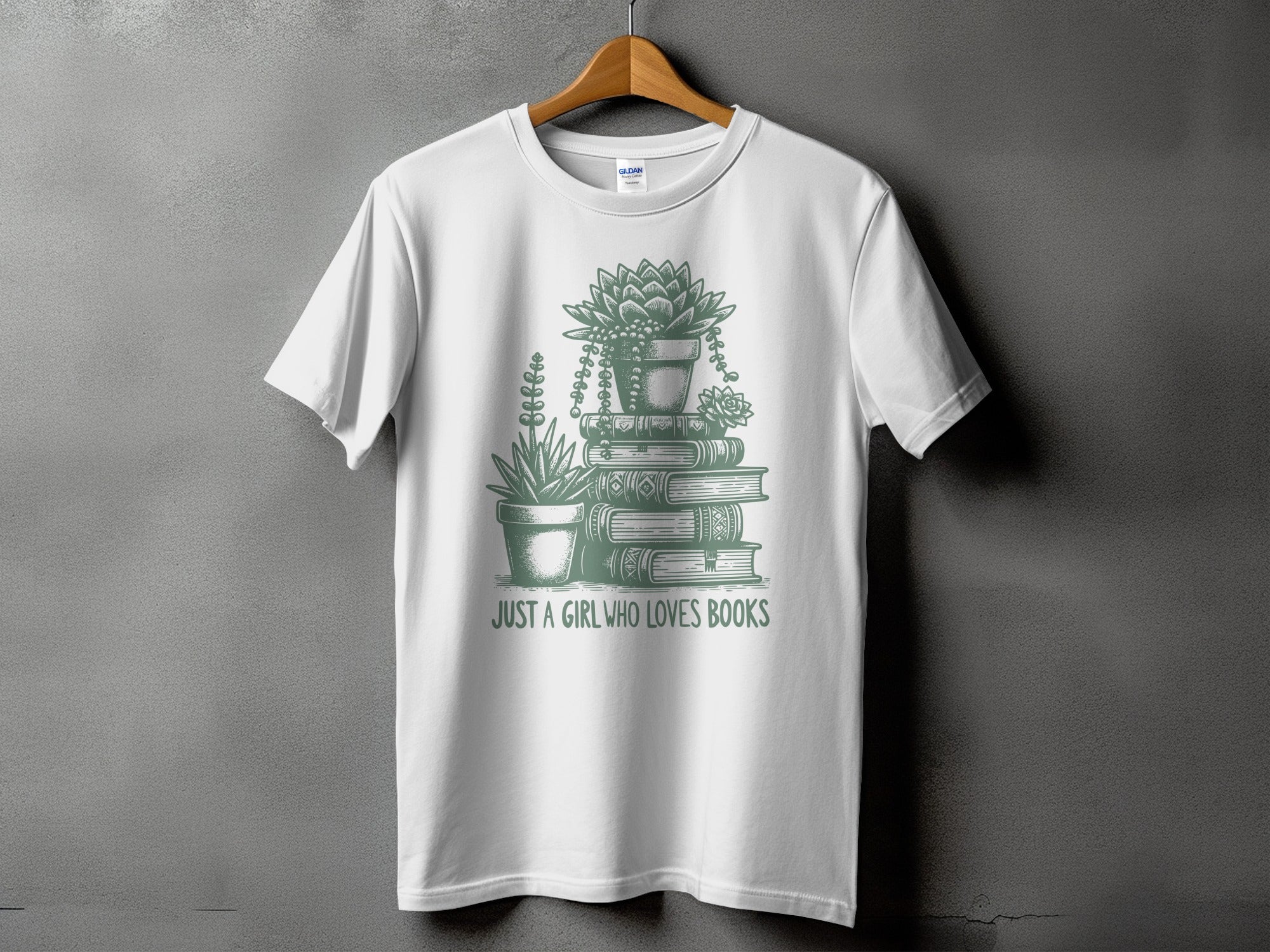 White t-shirt with green graphic of stacked books, potted succulents, and text "Just a girl who loves books".