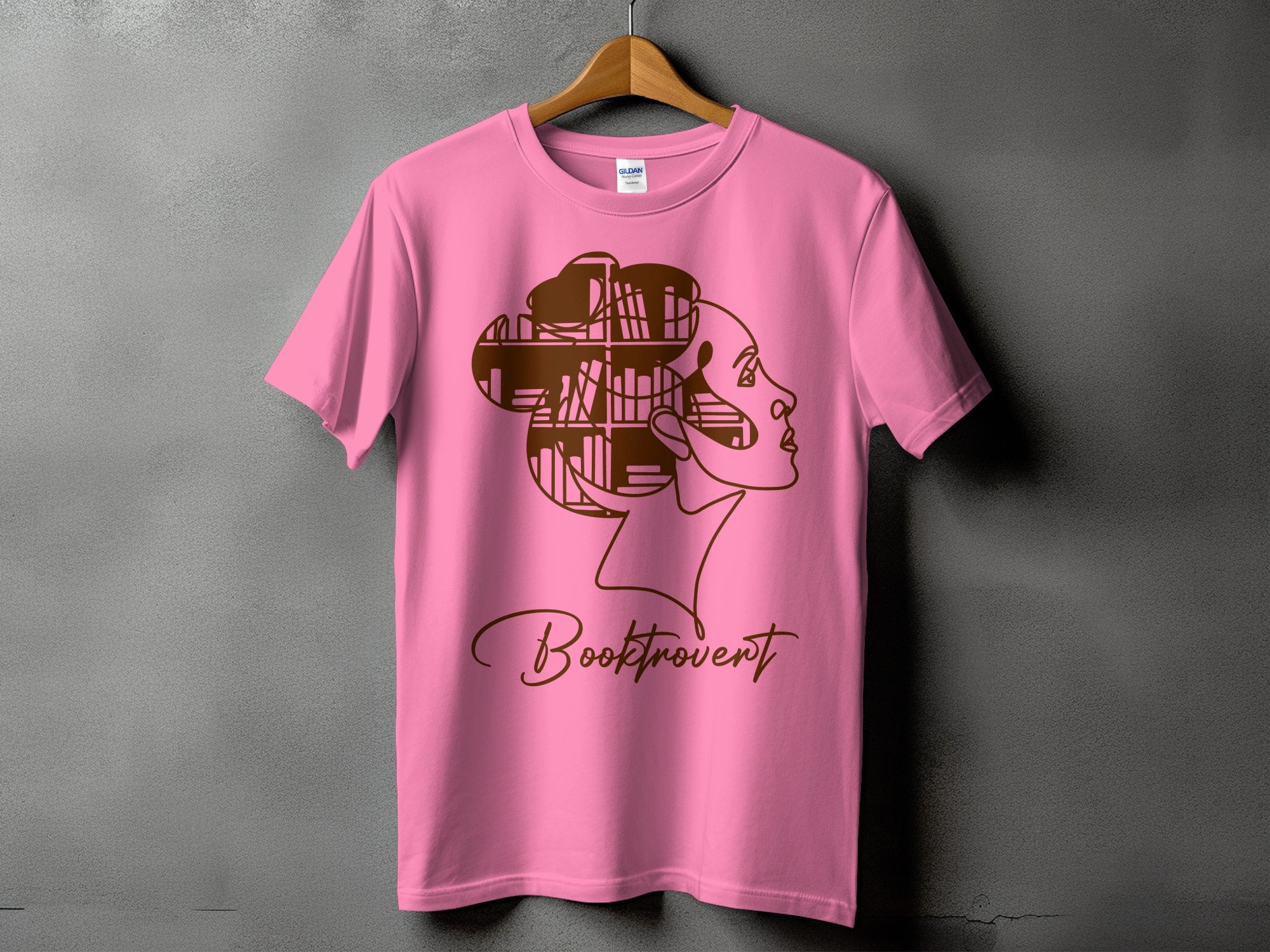 Pink t-shirt with brown outline of a profile with hair made of books and text "Booktrovert".