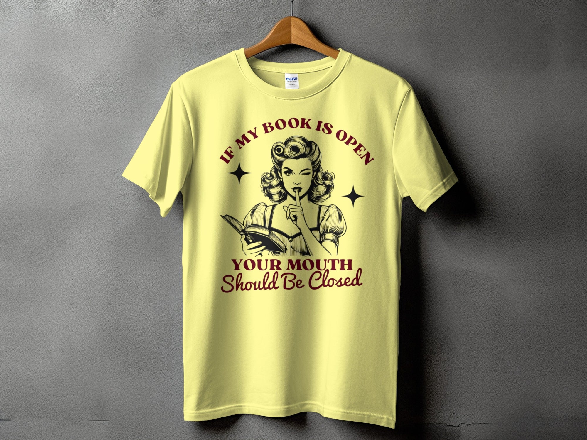 Yellow t-shirt with retro woman illustration and text "If my book is open, your mouth should be closed."
