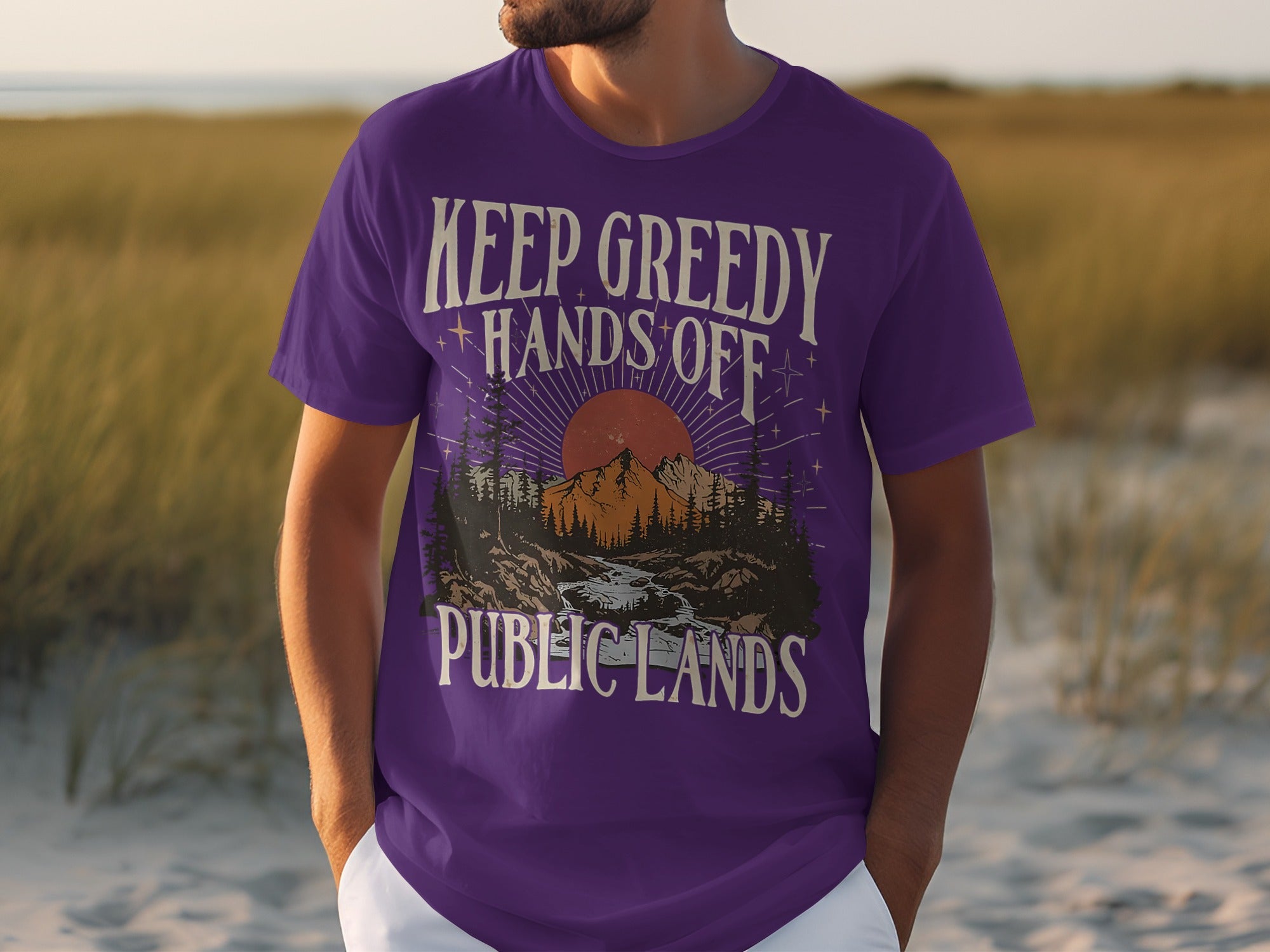 Purple t-shirt with text "KEEP GREEDY HANDS OFF PUBLIC LANDS" and mountain sunset graphic.
