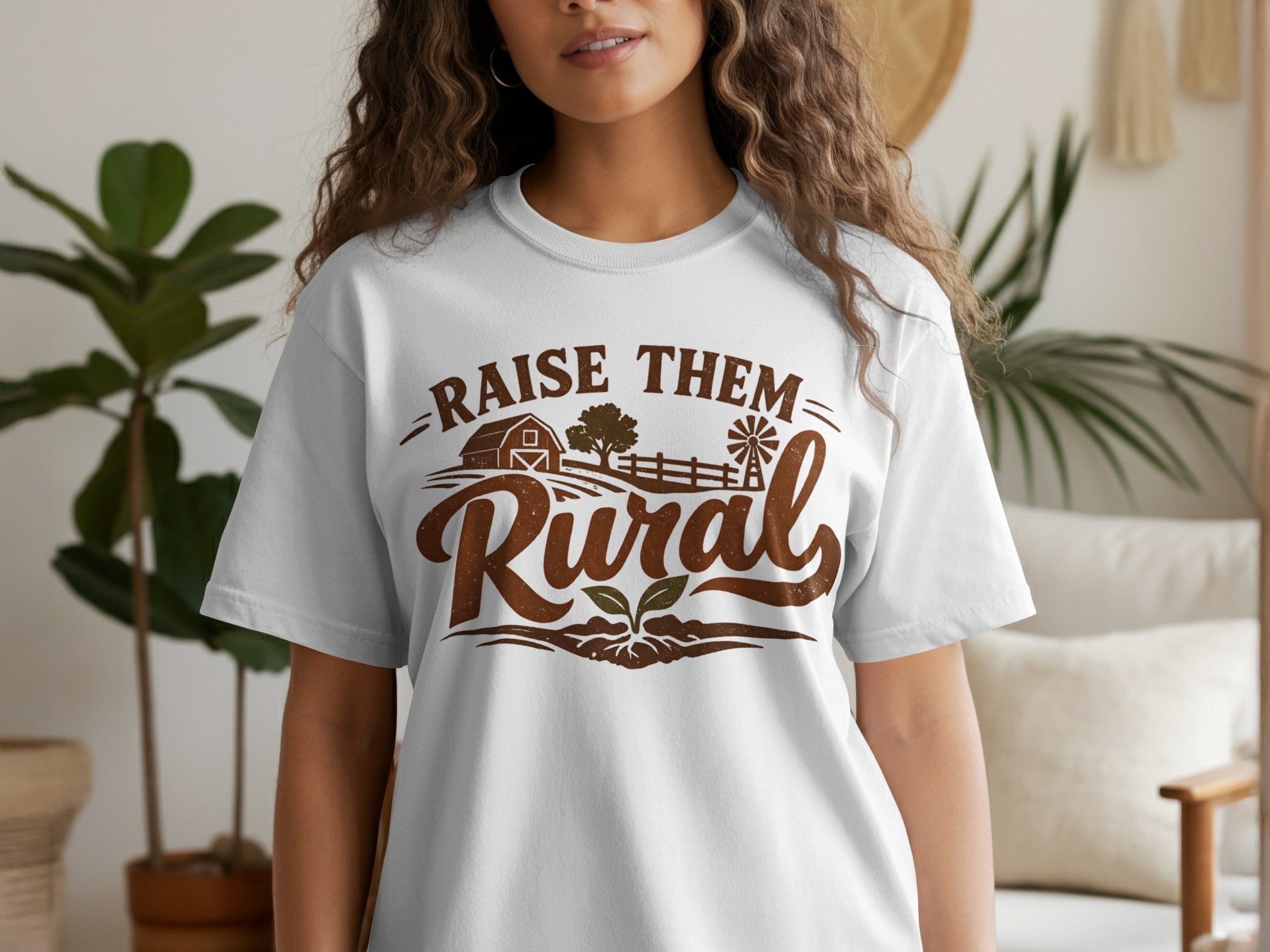 White t-shirt with distressed brown text that reads "Raise Them Rural" over a farm scene.