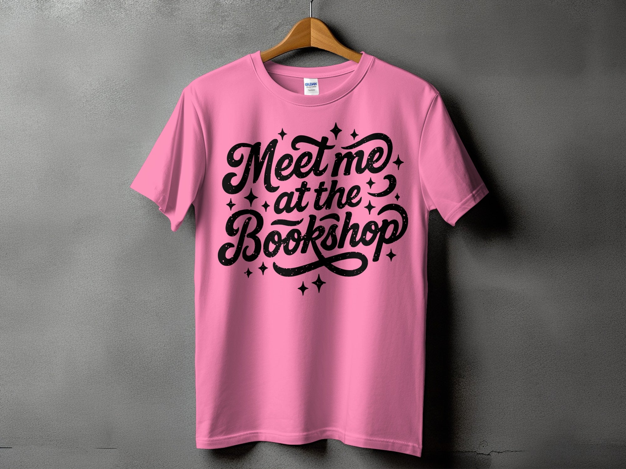 Pink t-shirt with black text reading "Meet me at the Bookshop".