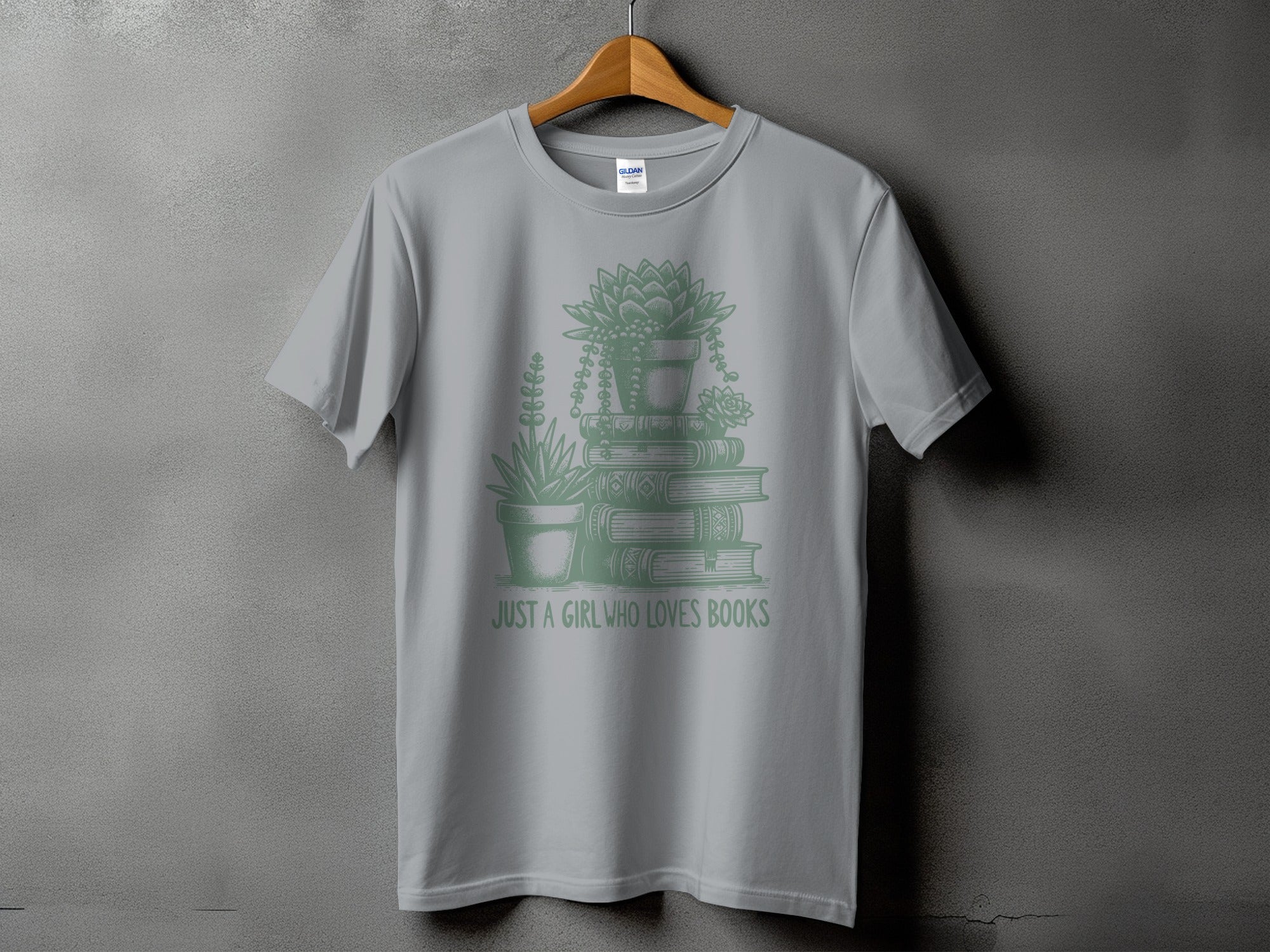 Grey t-shirt with stacked books and plants illustration and text.