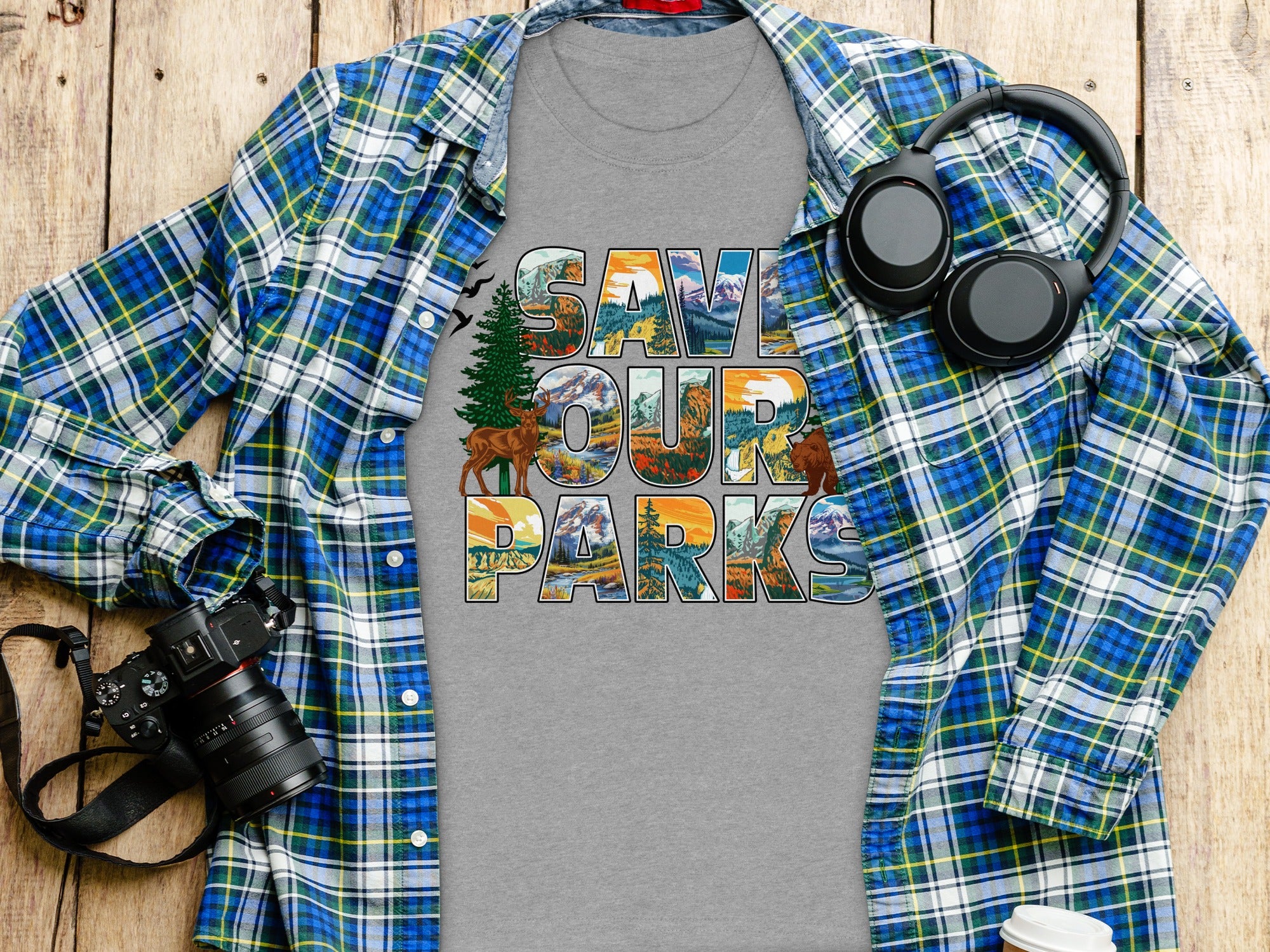 Grey t-shirt with "SAVE OUR PARKS" text featuring nature scenes, headphones, and camera.