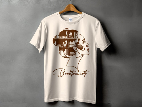 Cream t-shirt with brown line art of a woman's head, hair made of bookshelves, and the word "Booktrovert".