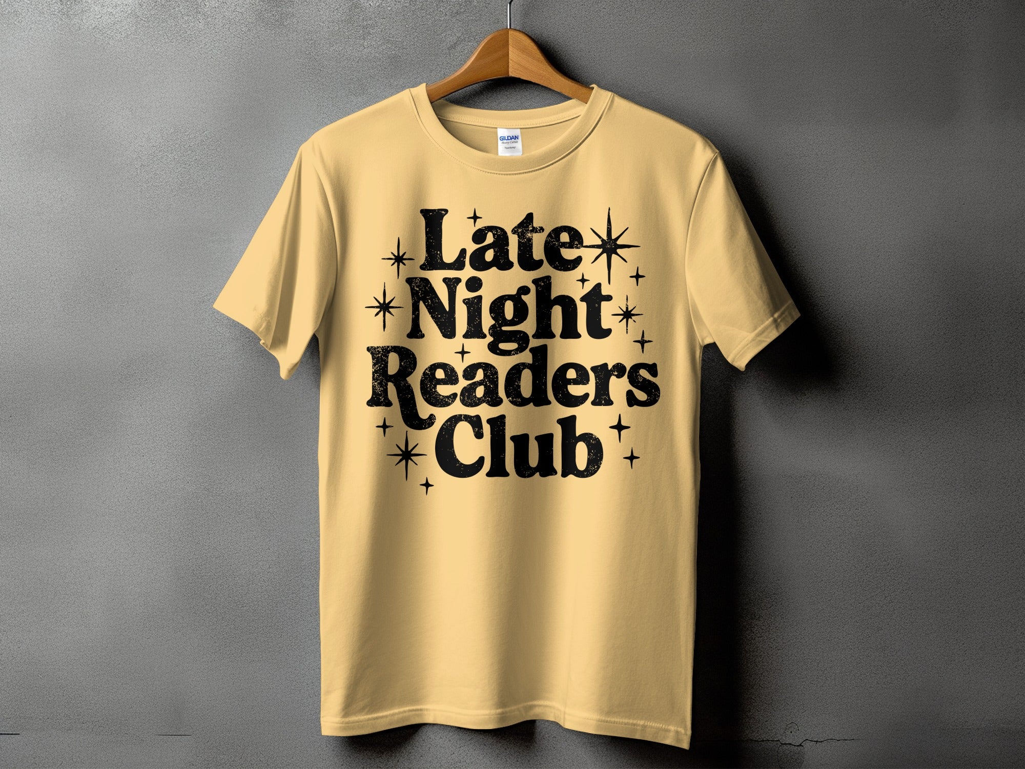 Yellow t-shirt with black text reading "Late Night Readers Club" and starburst accents.